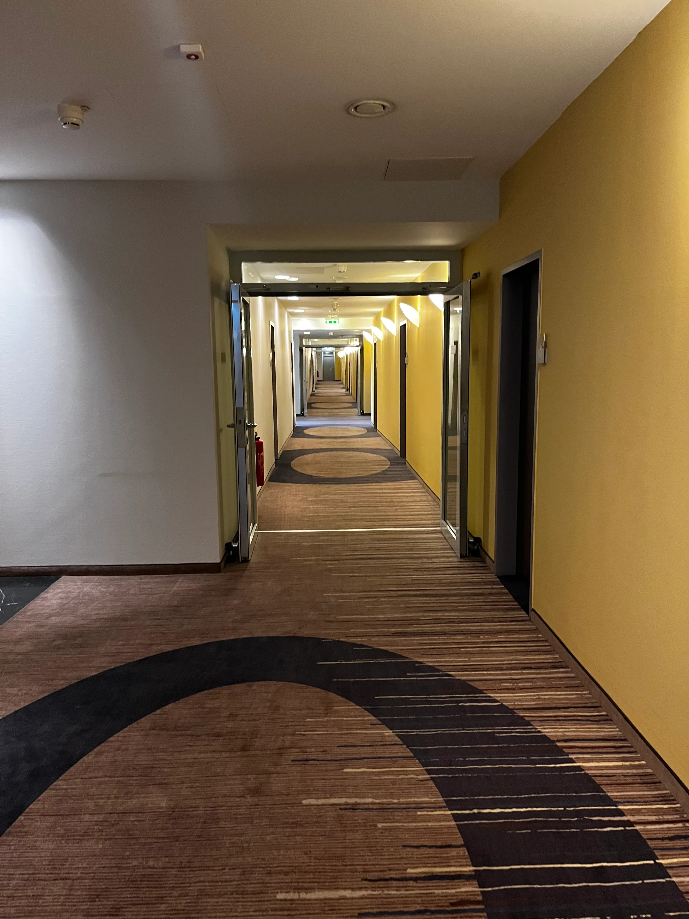 Gang im Hotel mit gelben Wänden und Teppichboden