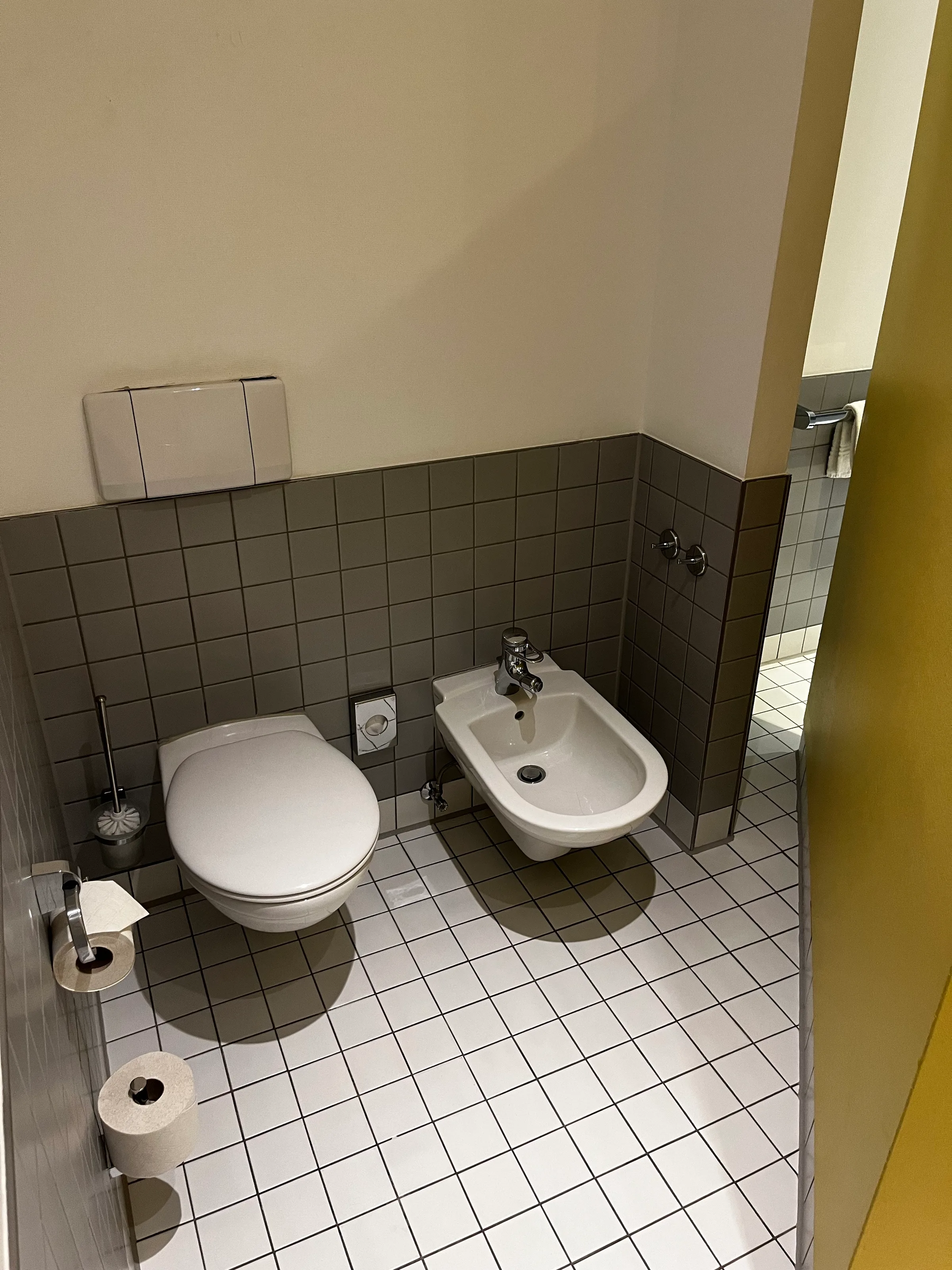 Hotel-WC mit Bidet und Toilette in grauen Fliesen