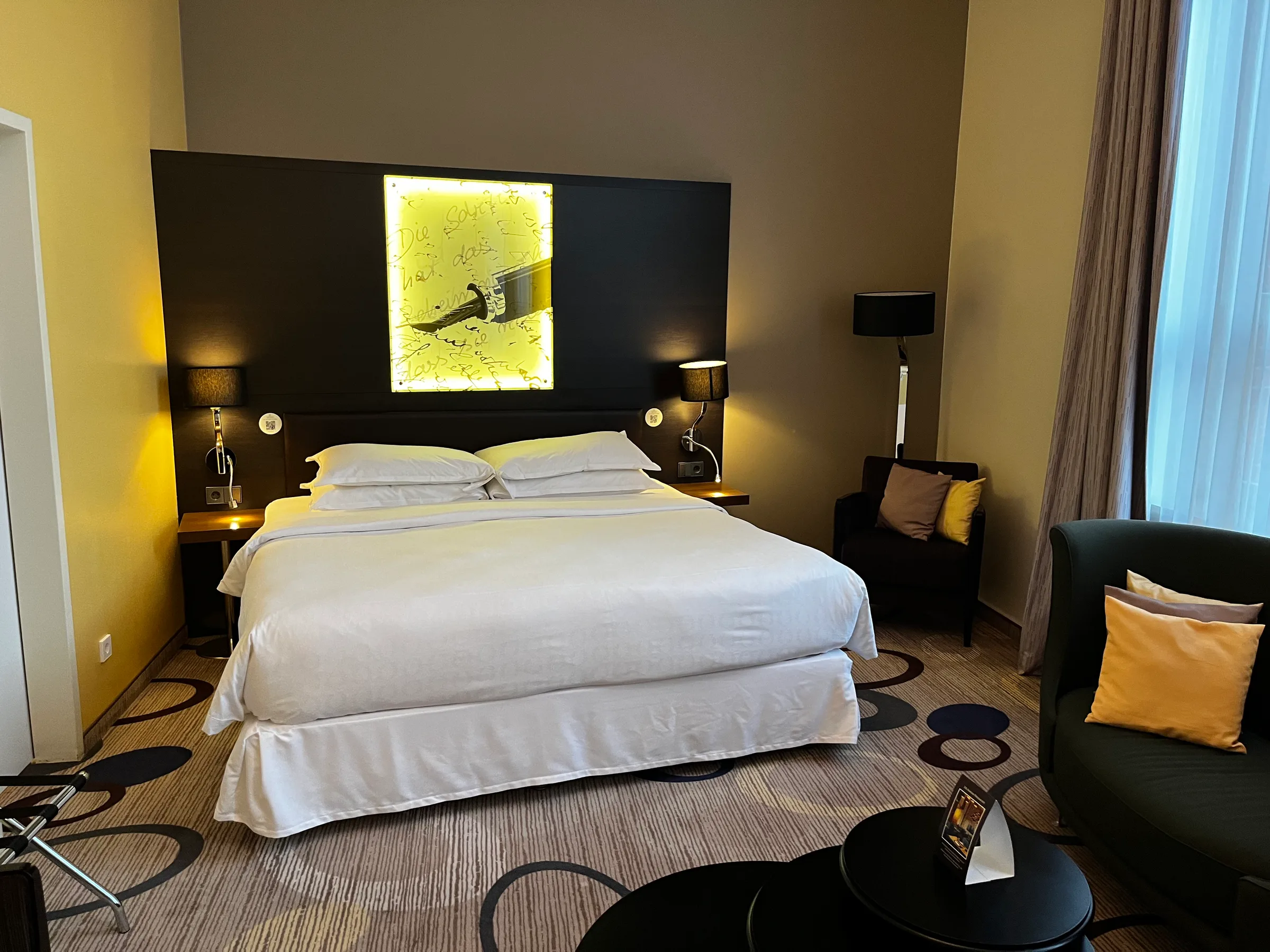Hotelzimmer mit Doppelbett und dekorativem Kopfteil in Grautönen