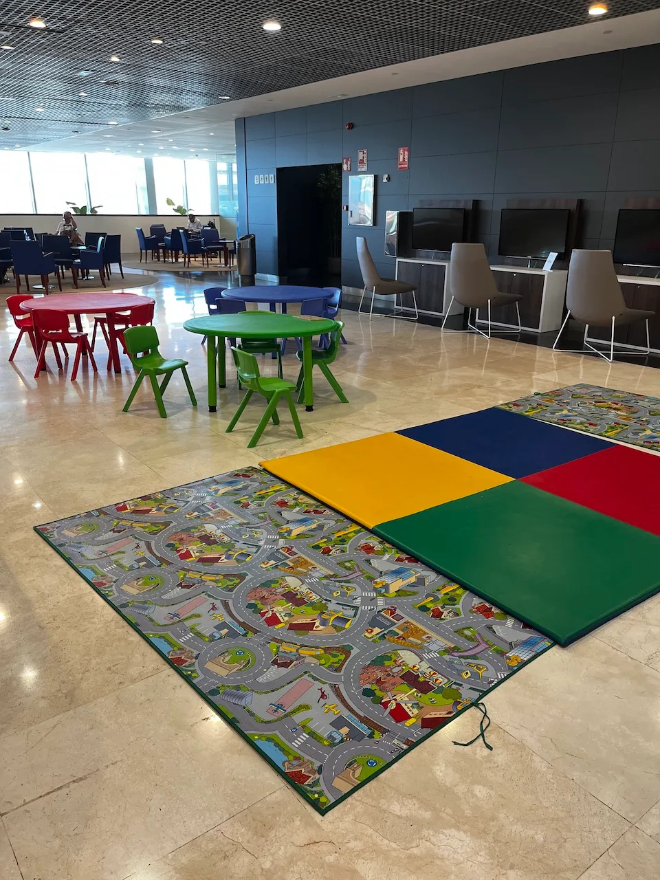 Kinderspielbereich mit bunten Platten und Kindertischen im Hotellobby