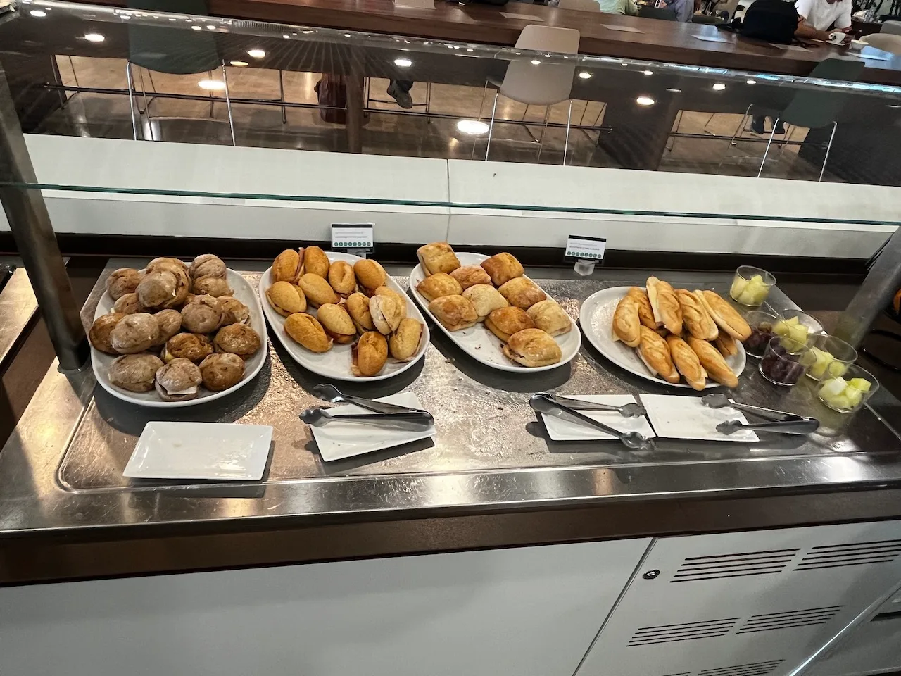 Frühstückstheke mit verschiedenen Gebäcksorten und Obstschalen