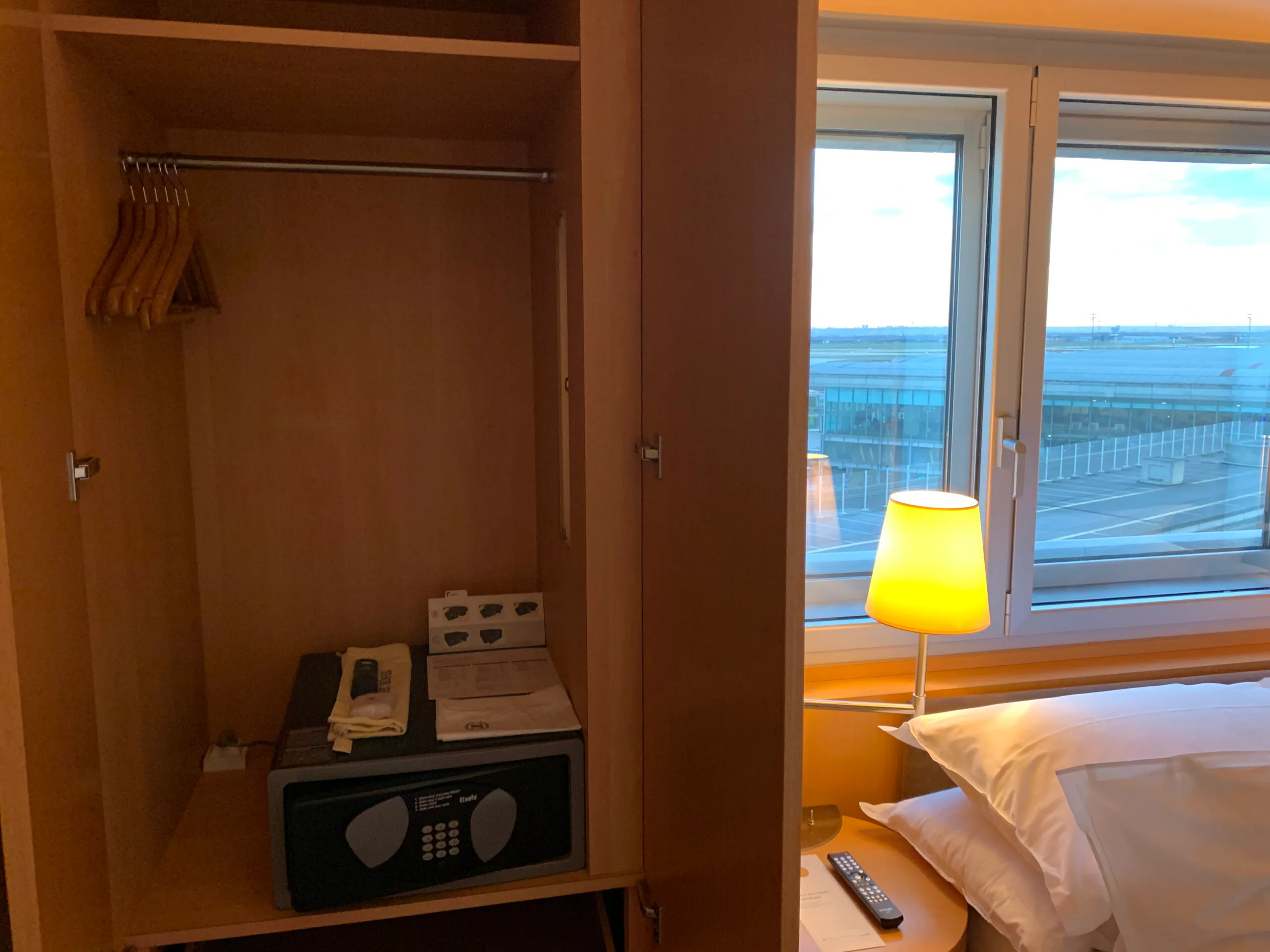 Hotelzimmer mit Kleiderschrank und Fensterblick auf Flughafen