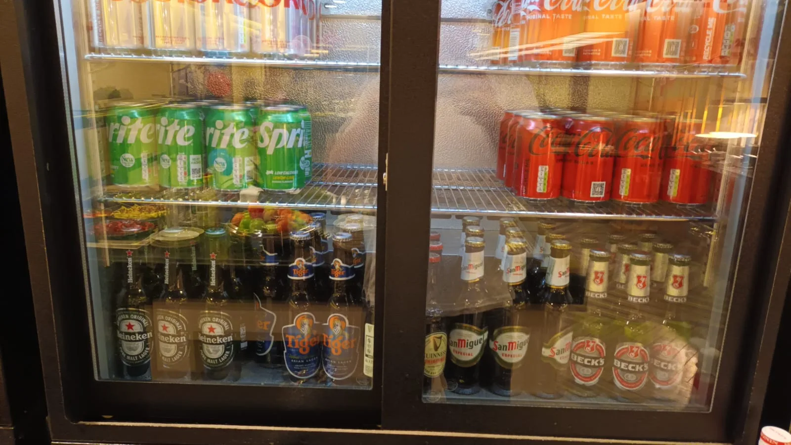 Getränkekühlschrank mit verschiedenen Getränken wie Sprite, Coca-Cola und Bier