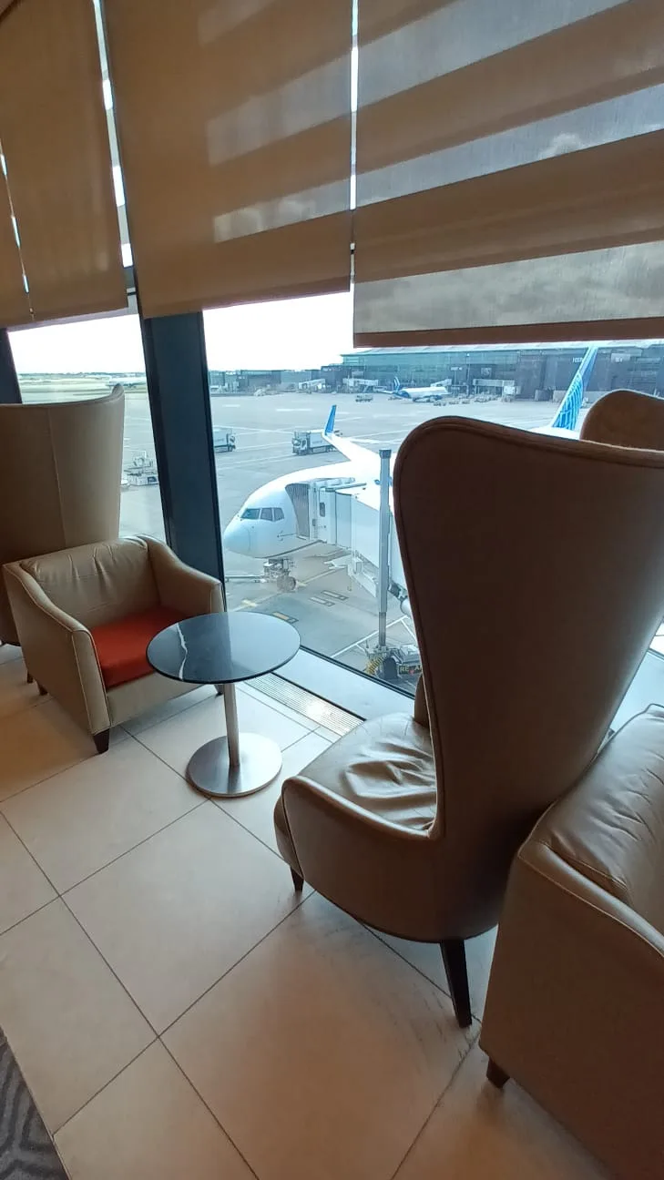 Lounge mit Sesseln und Tisch am Flughafenfenster