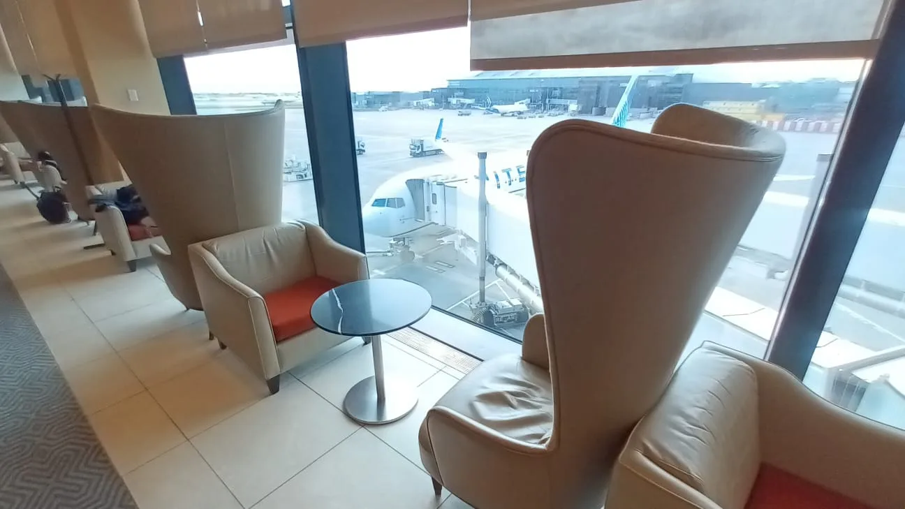 Lounge mit Sesseln und Tisch am Flughafenfenster