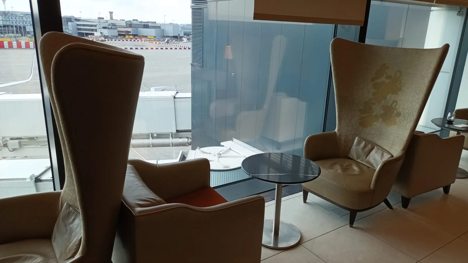 Lounge mit Sesseln und Tisch vor Flughafenfenster