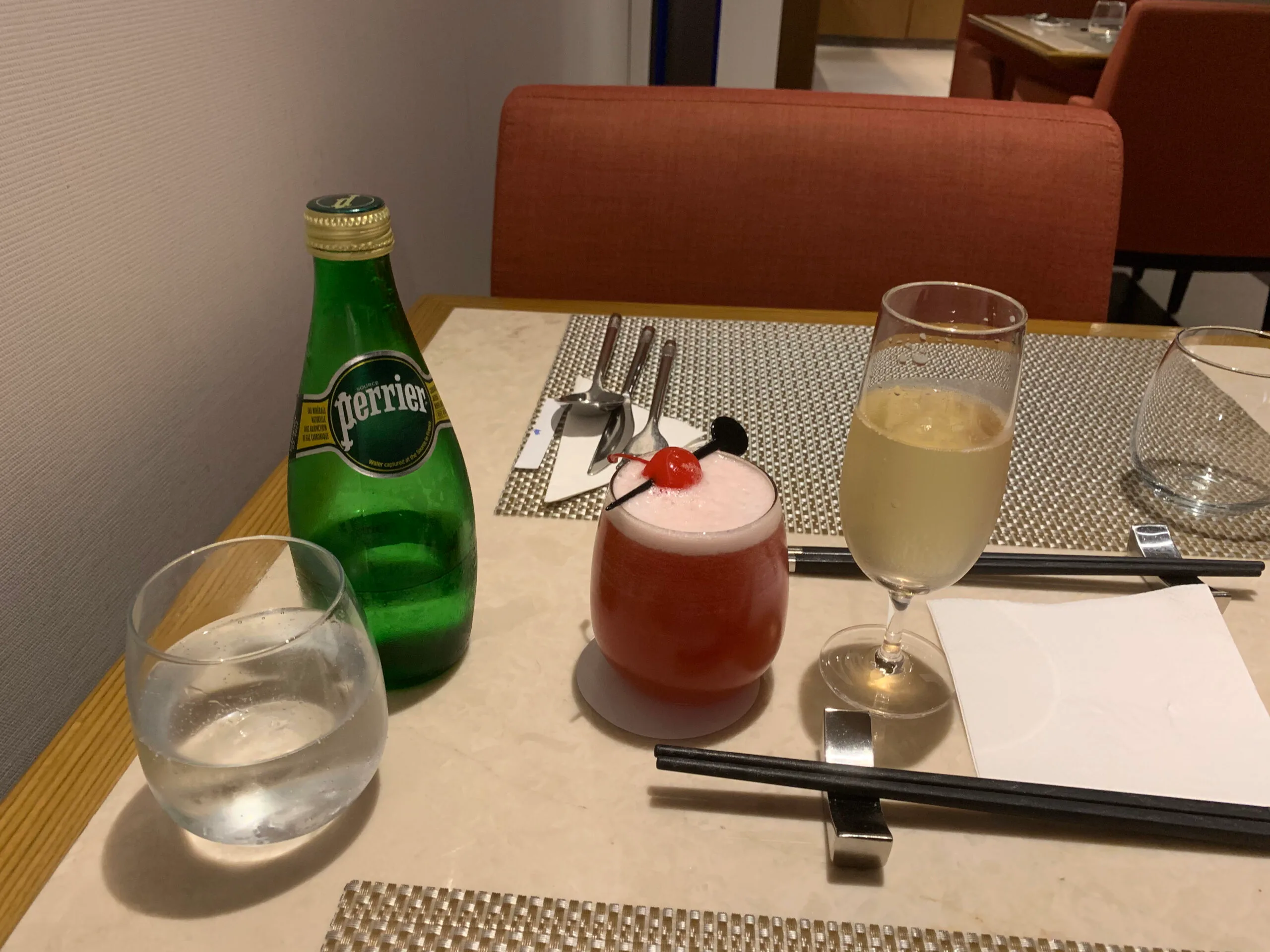 Tisch im First Class Lounge mit Perrier, Cocktail und Glas
