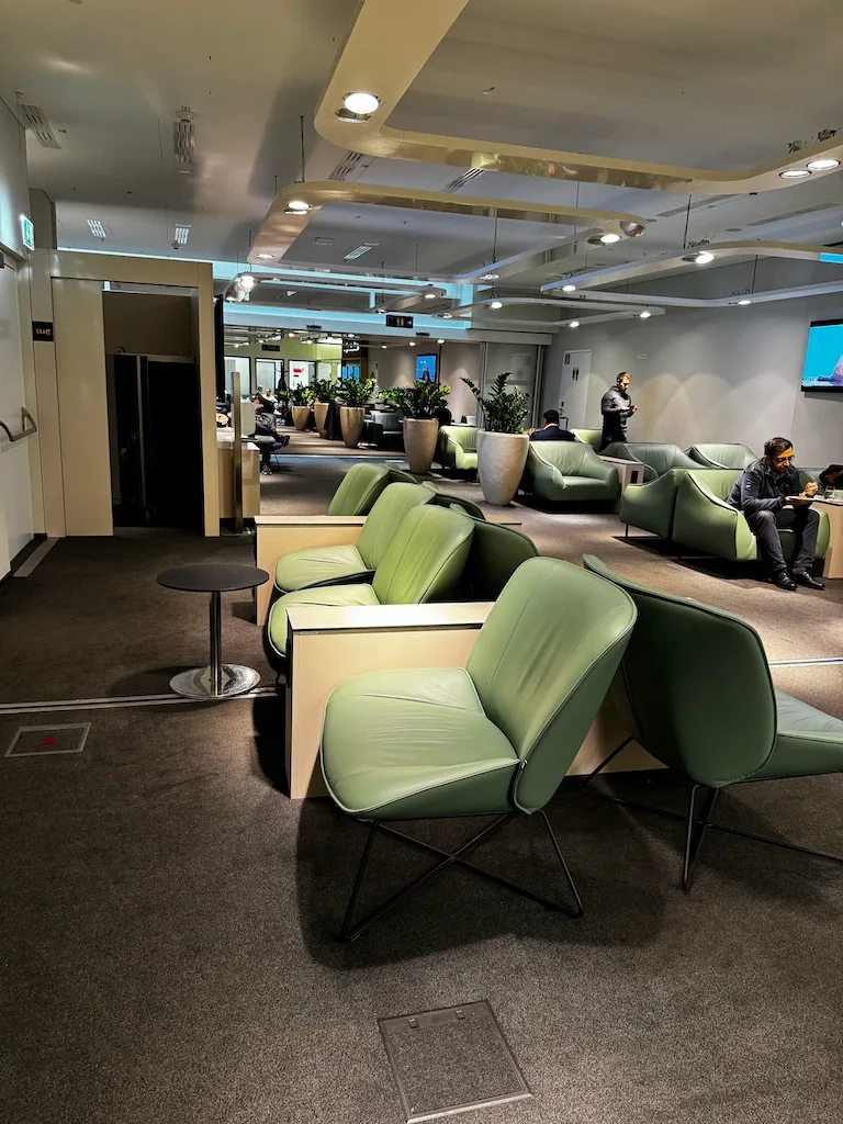 Wartebereich mit grünen Sesseln und Pflanzen im Flughafenlounge