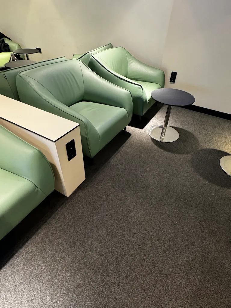 Lounge mit grünen Ledersesseln und kleiner Tisch im Flughafen