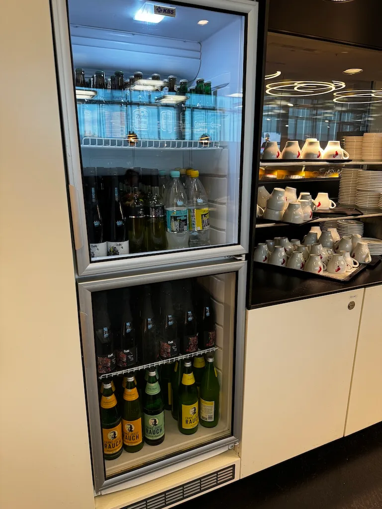 Kühlschrank mit Getränken und Geschirrregal im Sky Lounge Wien Flughafen