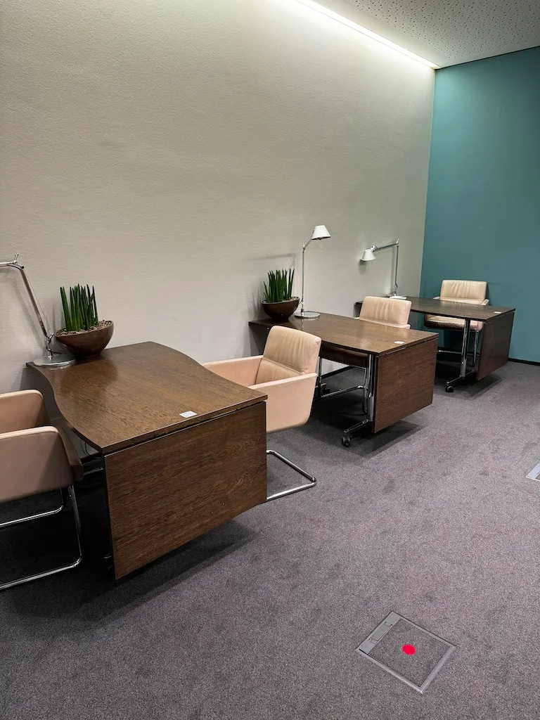 Lounge mit Holztischen und Sesseln in neutralen Farben