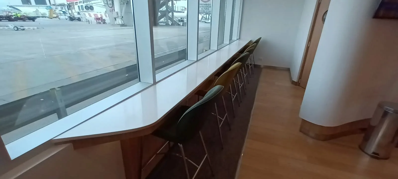 Lounge mit Tischen und Stühlen am Fenster mit Blick auf Flughafen