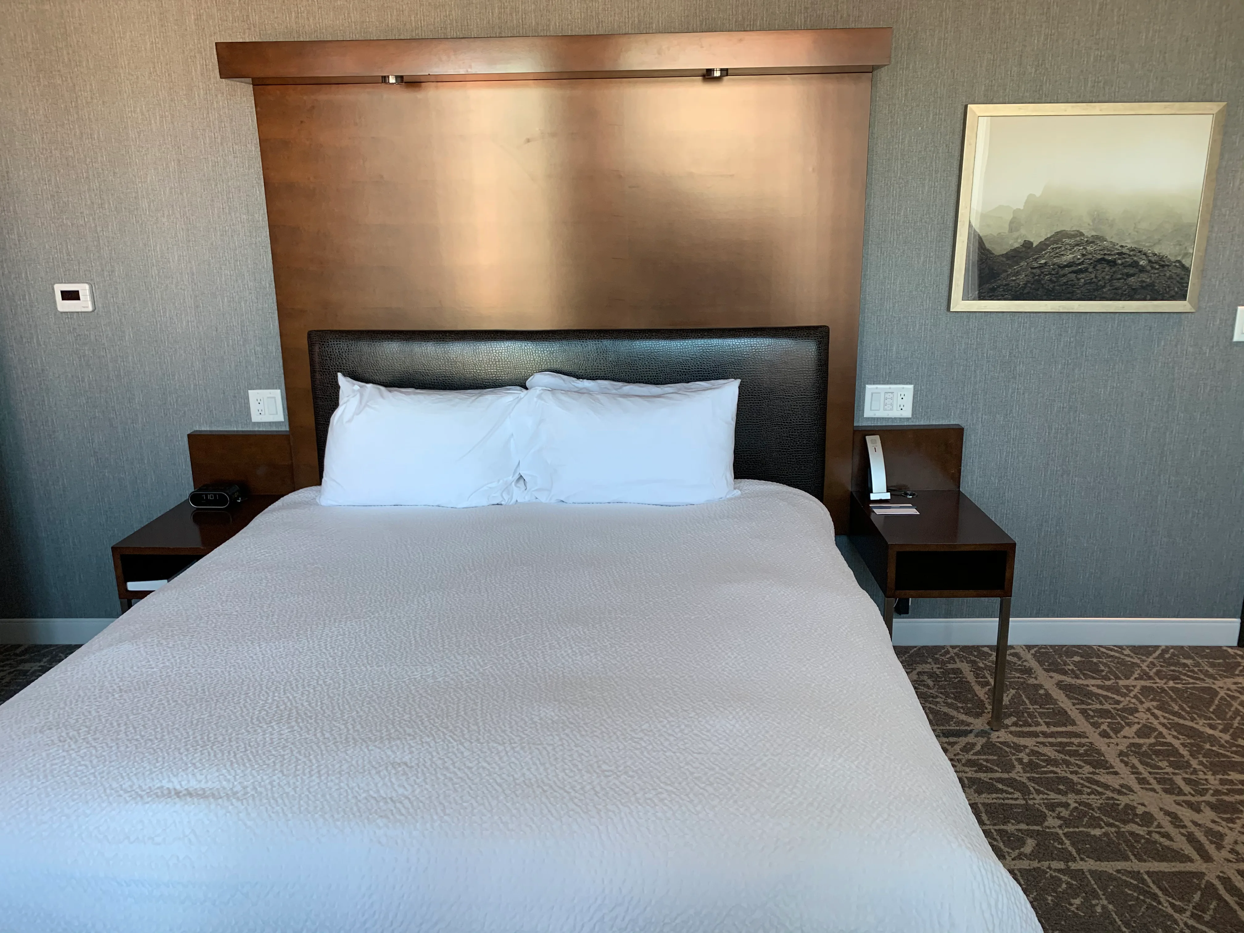 Doppelbett im Hotelzimmer mit grauem Kopfteil und Kissen