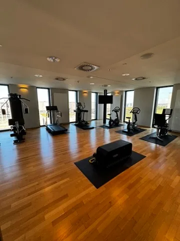 Fitnessraum mit verschiedenen Trainingsgeräten und Holzboden
