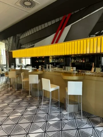 Bar mit gelben Paneelen und weißen Barhockern im Flughafenhotel