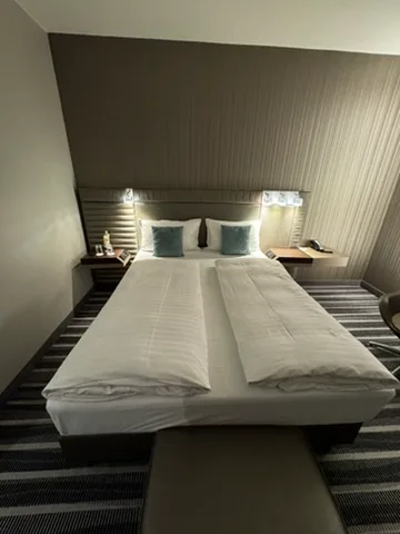 Doppelbett im Hotelzimmer mit grauen Akzenten