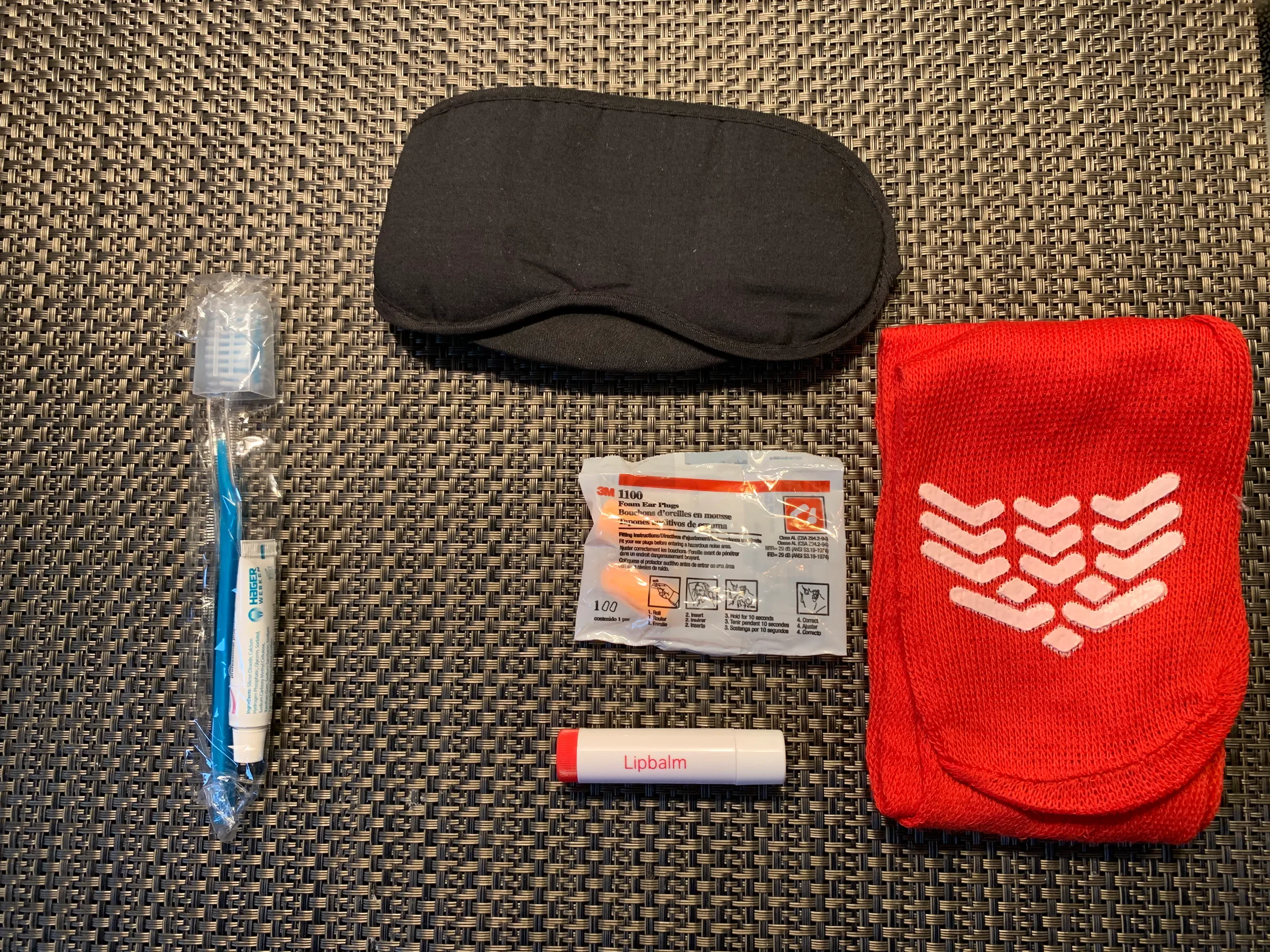 Schlafmaske, Ohrenstöpsel, Lippenbalsam, Zahnbürste und Tasche in einer Swiss Business Class Gepäcktasche