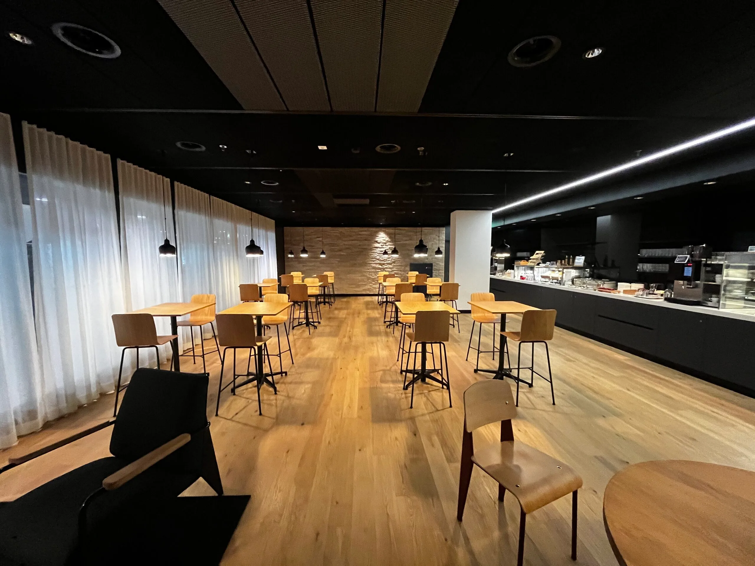 Bar mit Sitzhockern und Flaschenregalen im Loungebereich