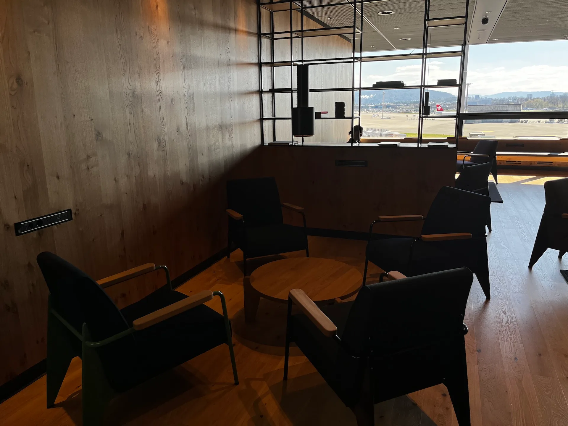 Lounge mit Sesseln und Tisch vor Flughafenausblick