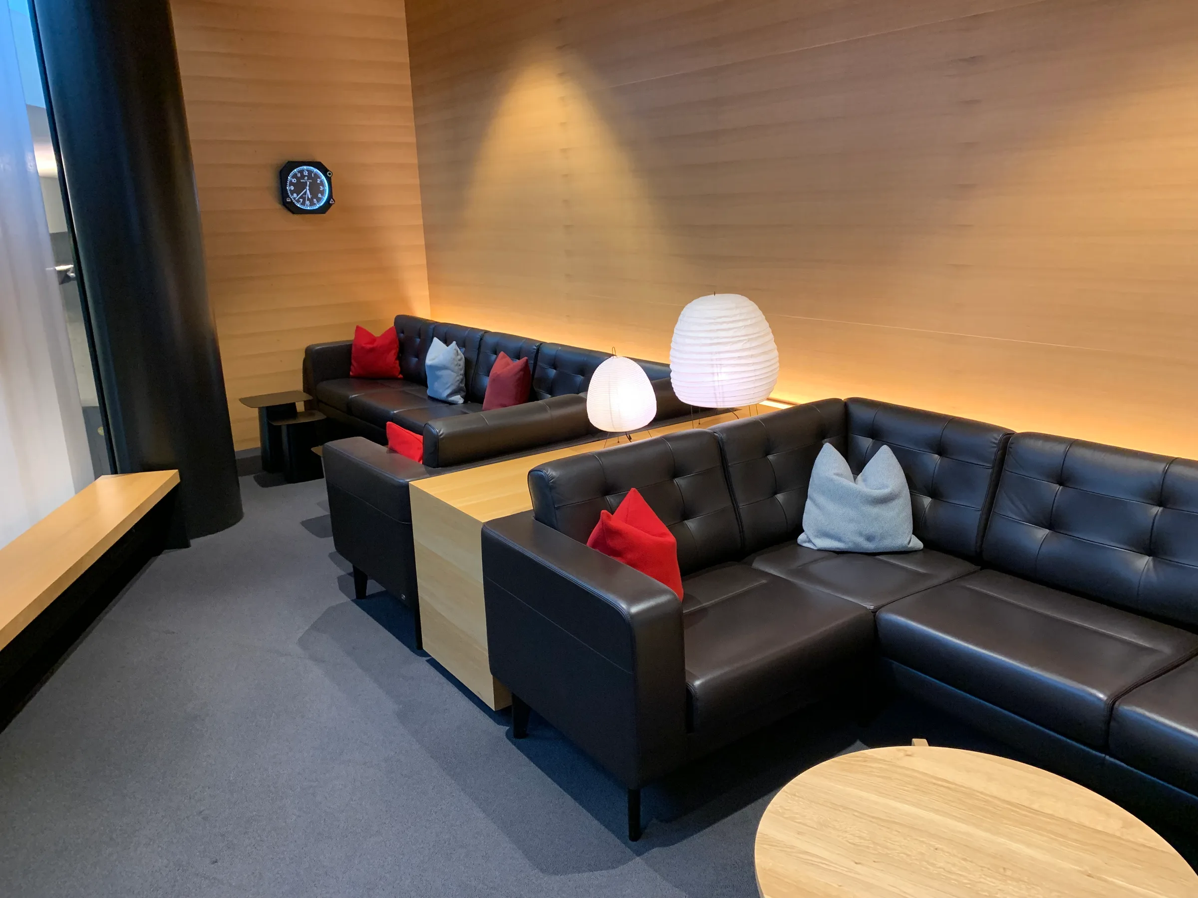 Lounge mit schwarzen Ledersofas und dekorativen Kissen