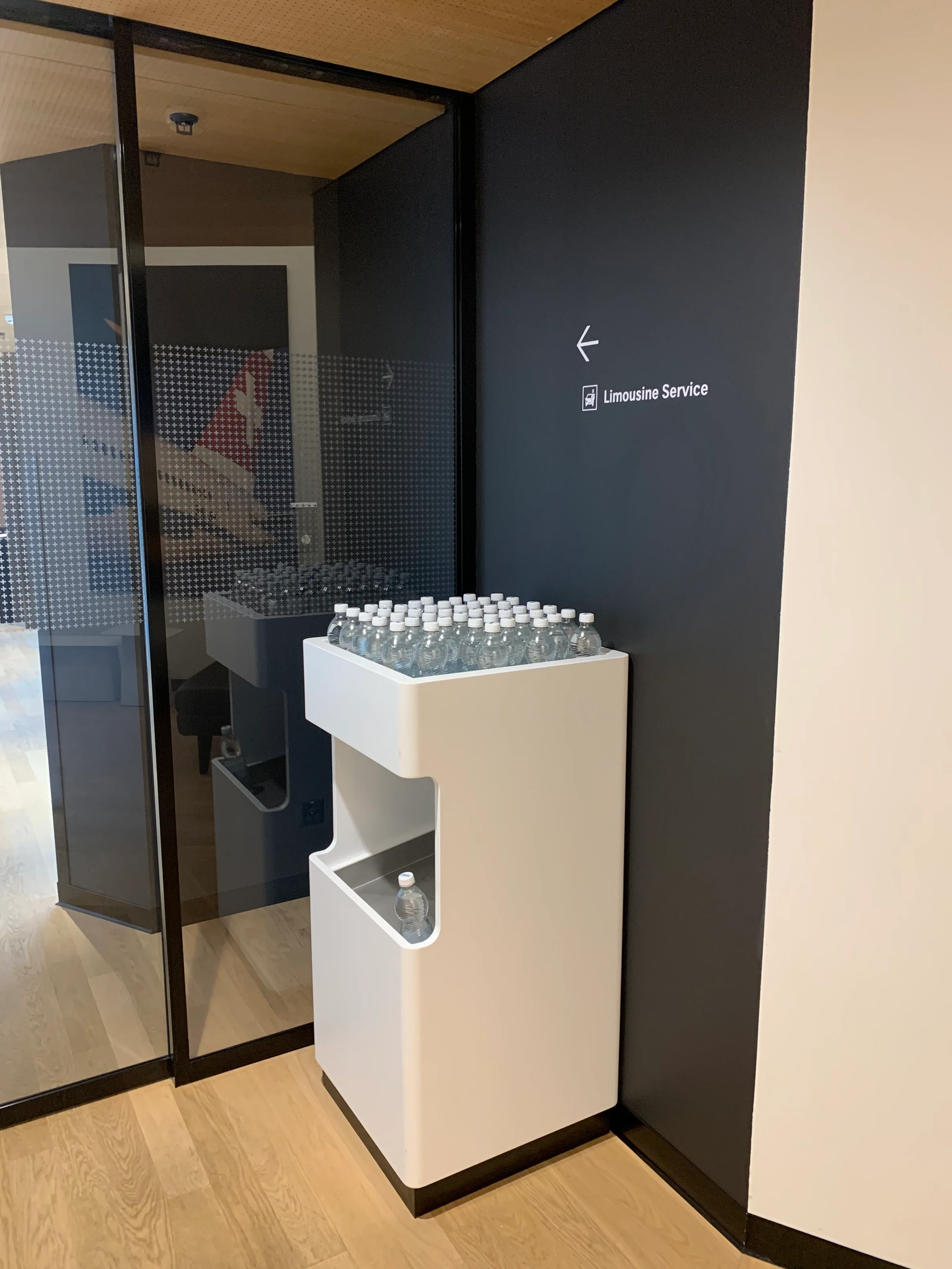 Wasserflaschen auf weißem Regal vor schwarzer Wand
