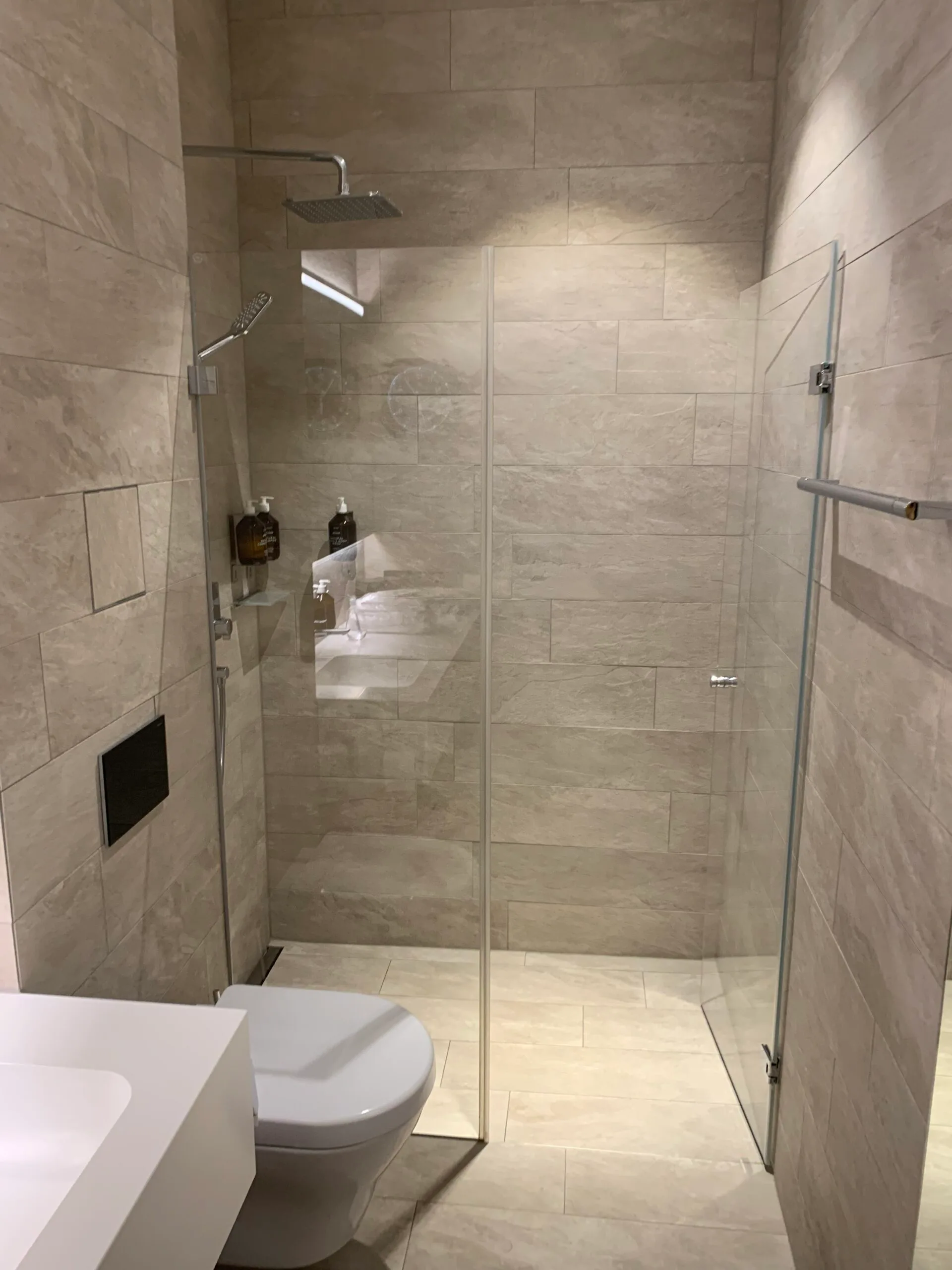 Moderne Dusche mit Glaswand und Regenbrause im Flughafenlounge