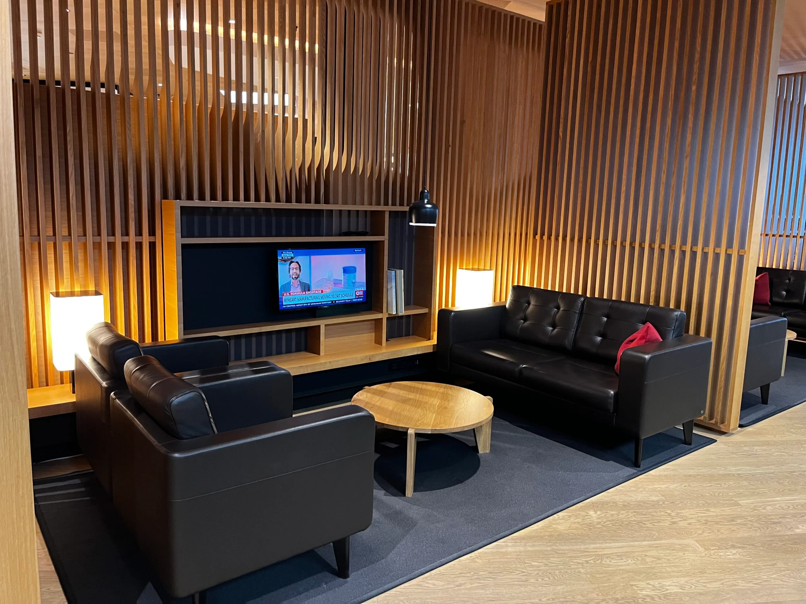 Lounge mit schwarzen Ledersofas und Holzwänden