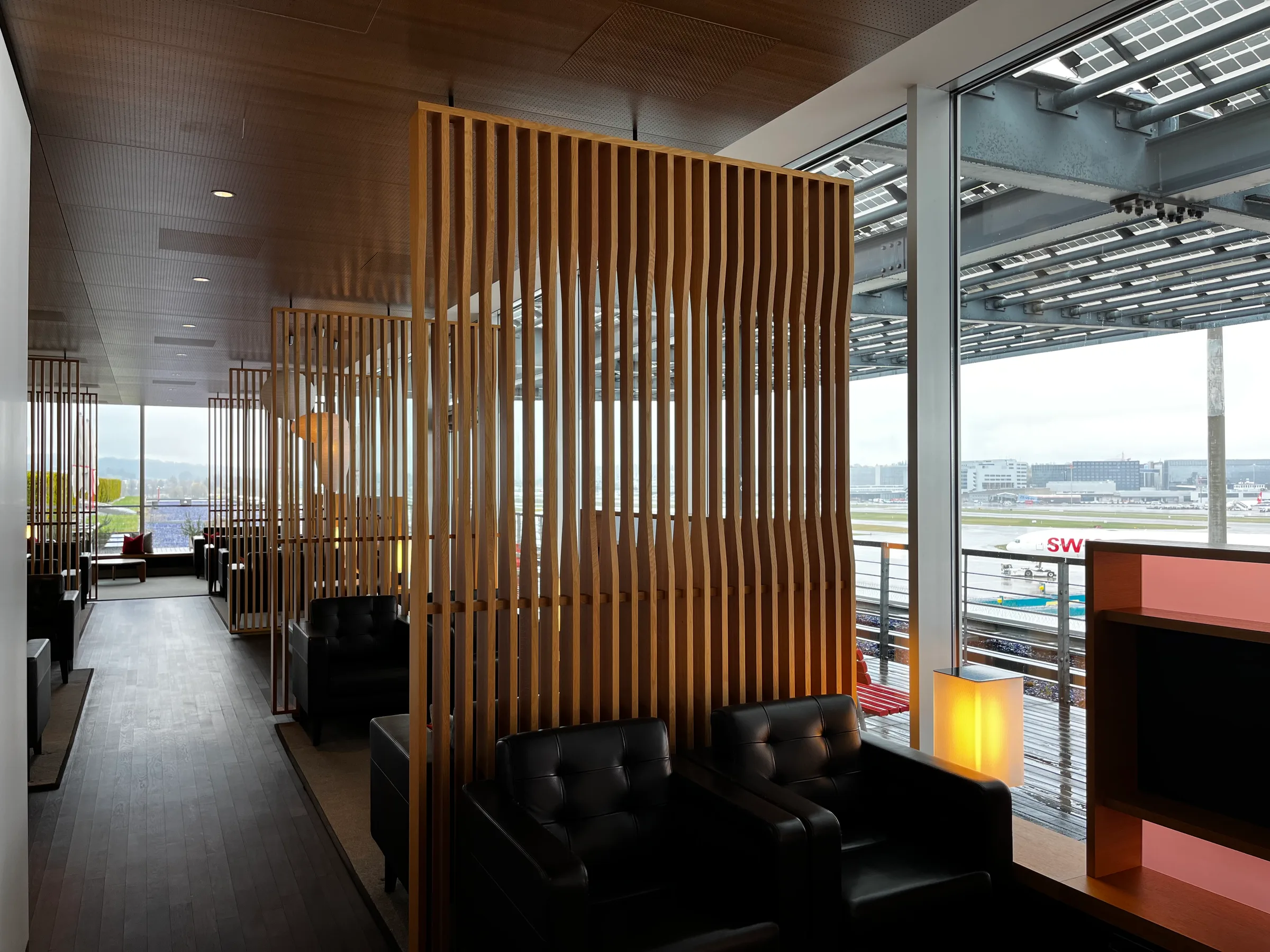 Holzschirm als Trennwand in First Class Lounge mit Blick auf Flughafen