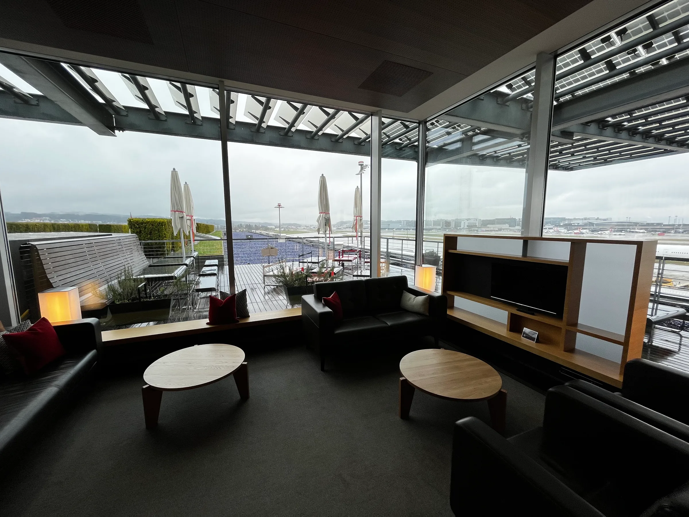 Lounge mit Sesseln und Couchen mit Blick auf Flughafen