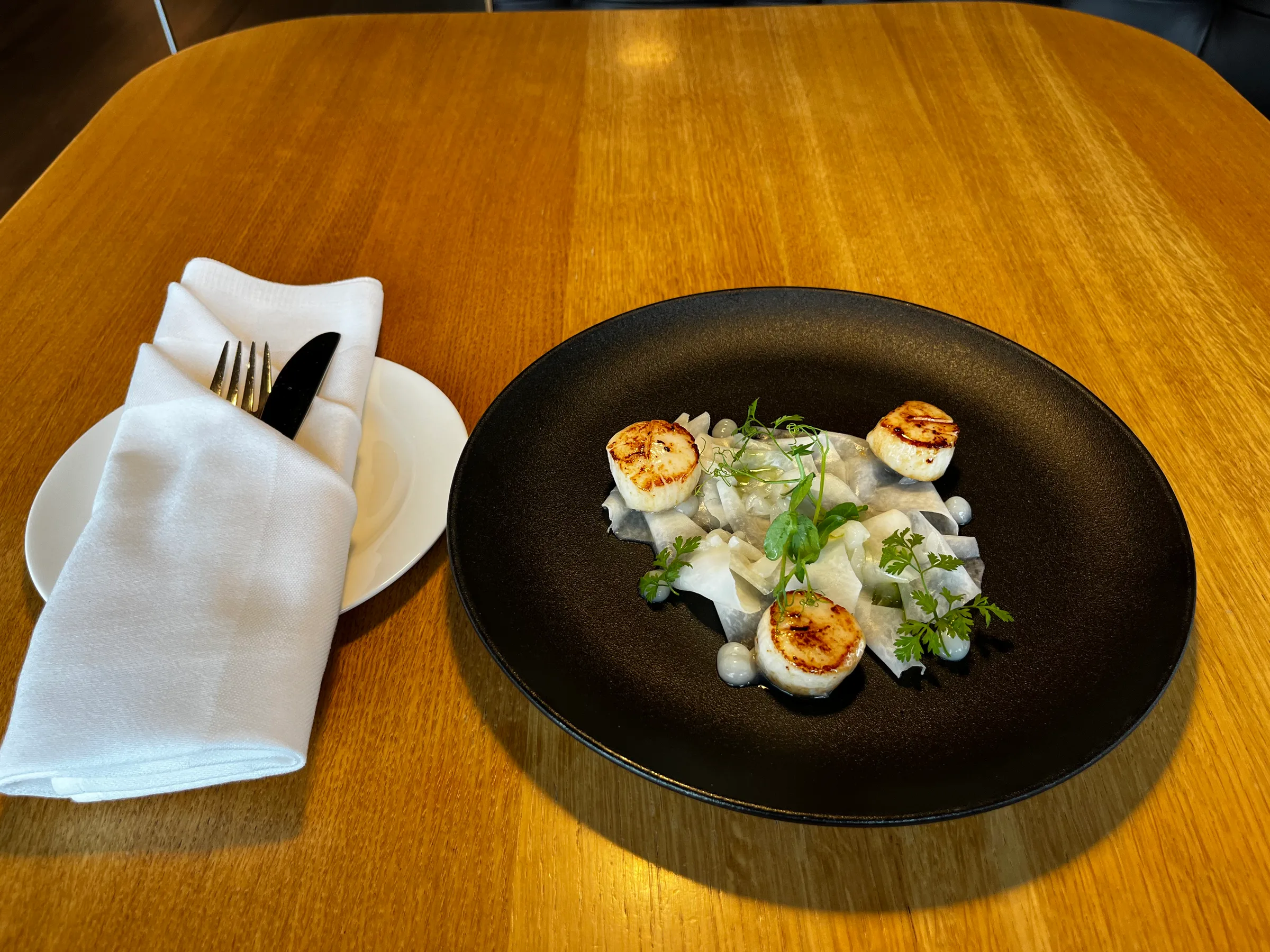 Gedeckter Tisch mit Serviette und Besteck auf Holztisch