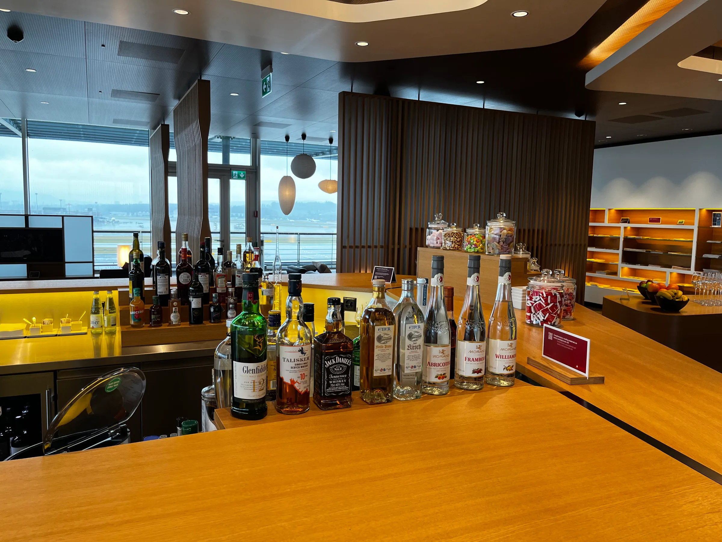 Bar mit verschiedenen Spirituosenflaschen und Süßigkeiten auf Holztisch