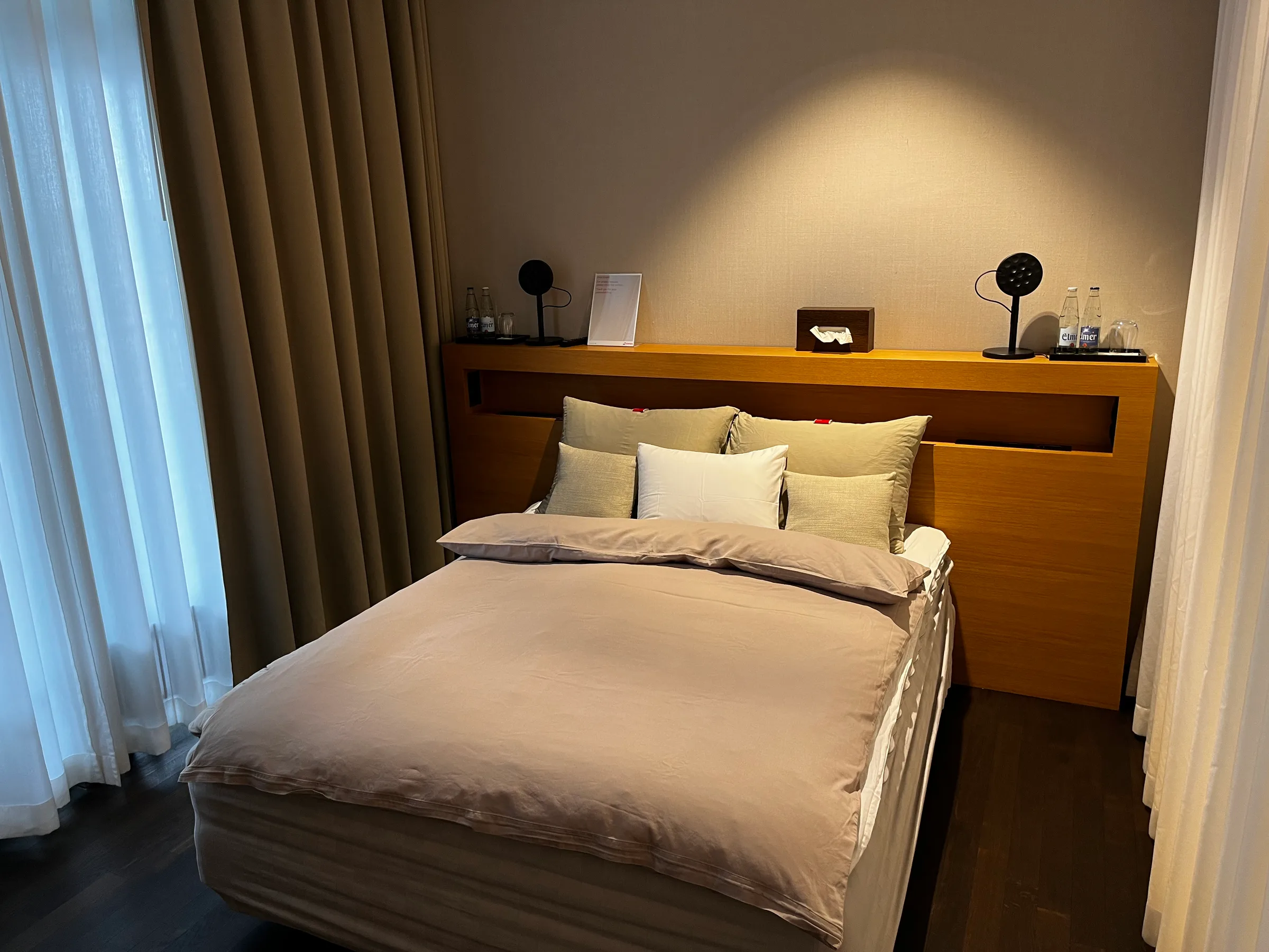 Doppelbett im Hotelzimmer mit grauem Bettbezug und Kissen
