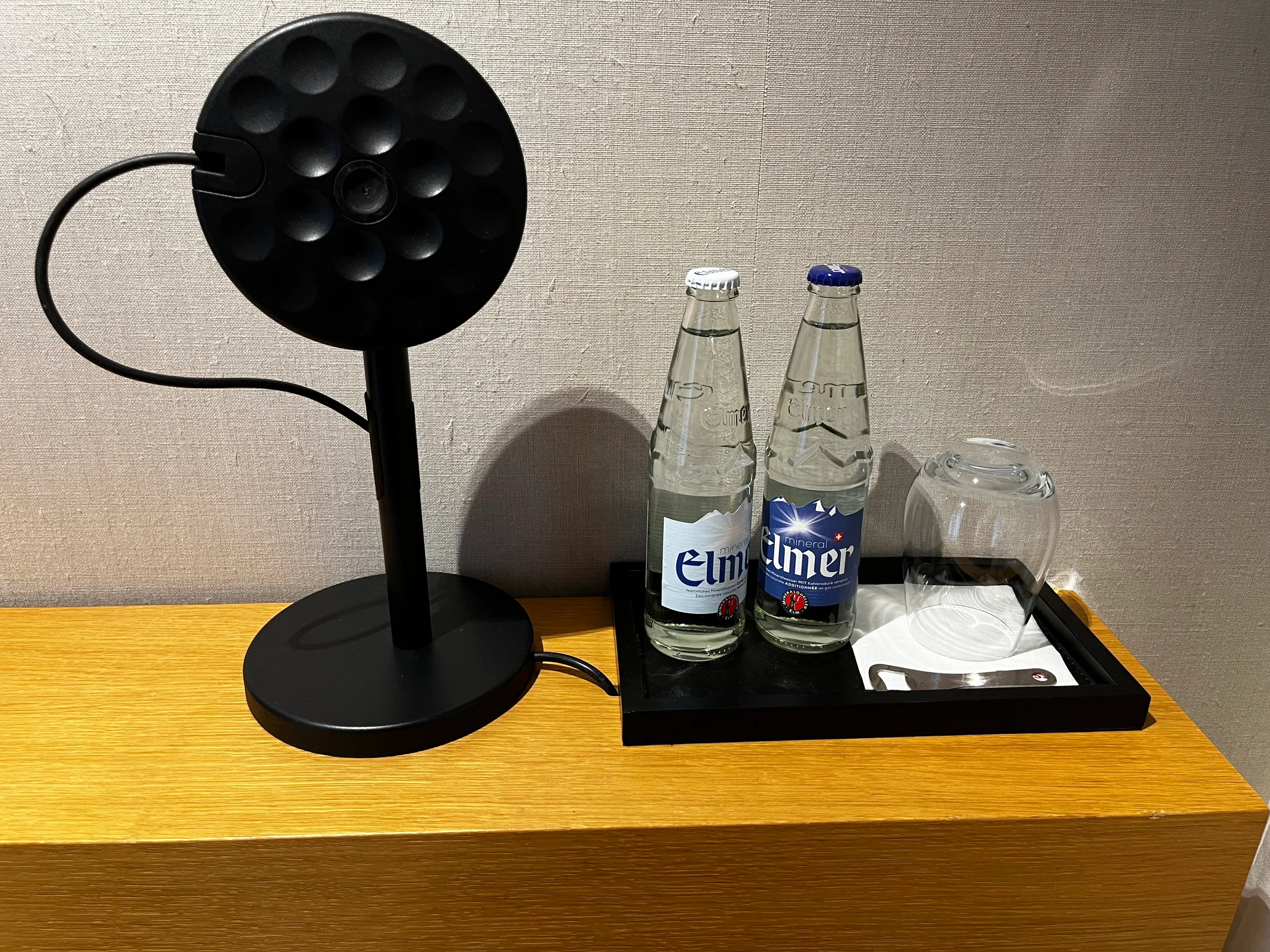 Schwarze Lampe auf Holztisch mit Flaschen und Glas
