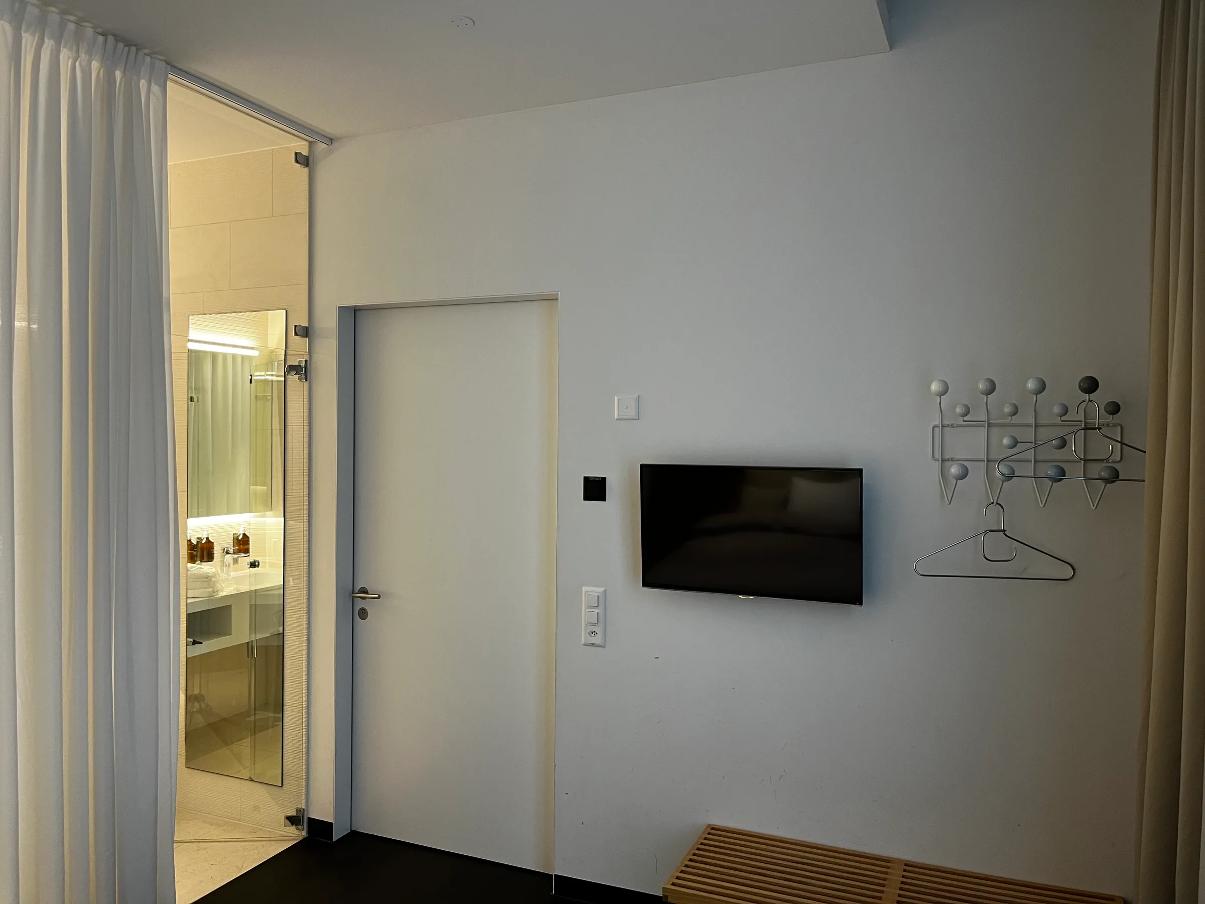 Schlichtes Hotelzimmer mit Flachbildfernseher und Garderobe
