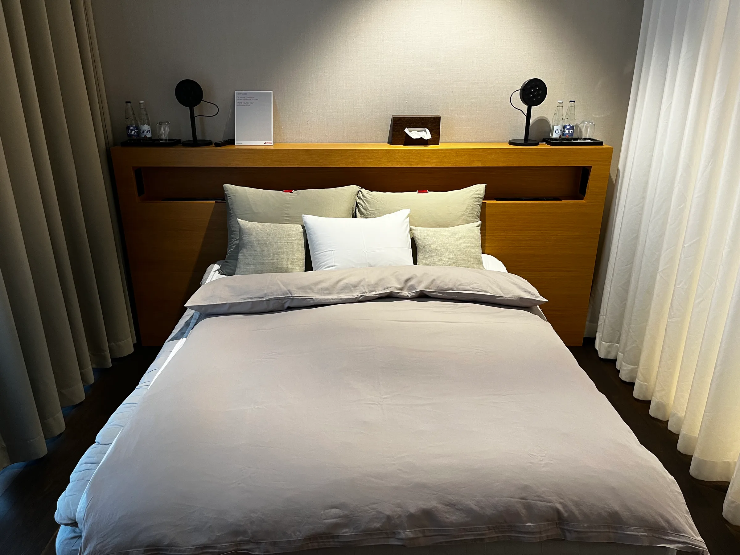 Doppelbett im Hotelzimmer mit grauem Laken und Kissen