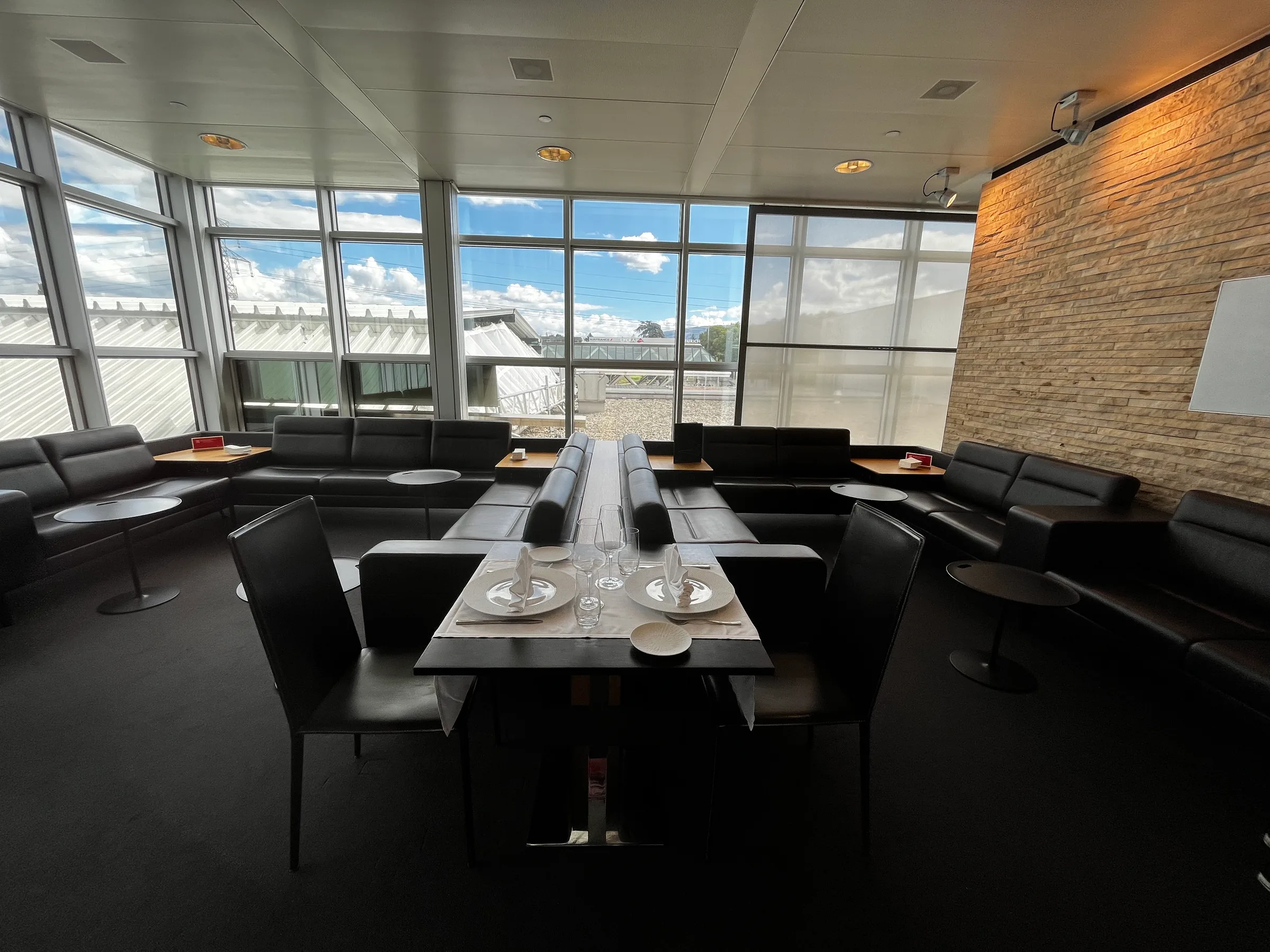 Lounge mit Sesseln und Tischen vor Panoramafenstern