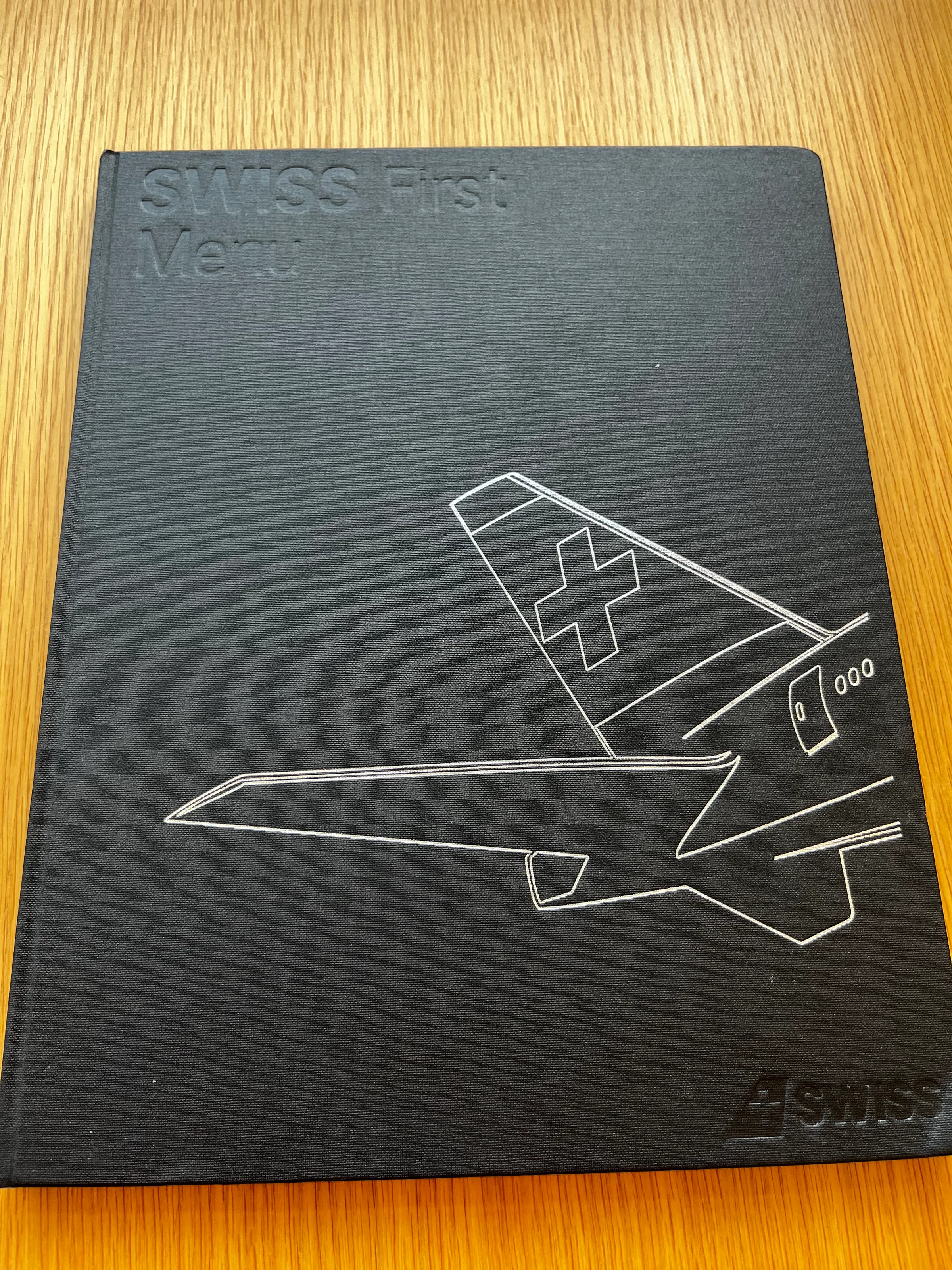 Schwarzes Buch mit Flugzeugdarstellung und Schweizer Flagge auf Cover