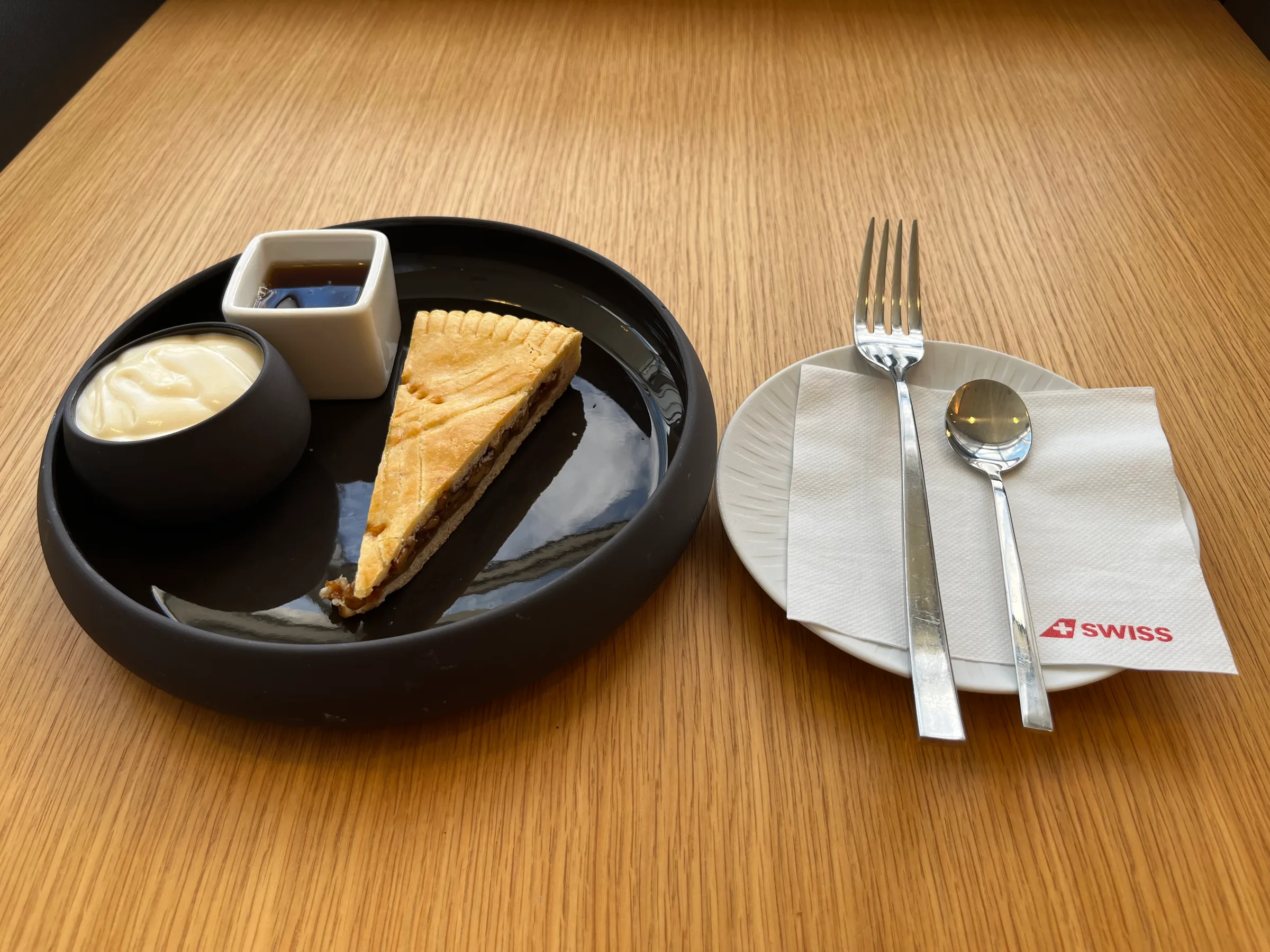 Stück Kuchen auf Teller mit Sahne und Sirup