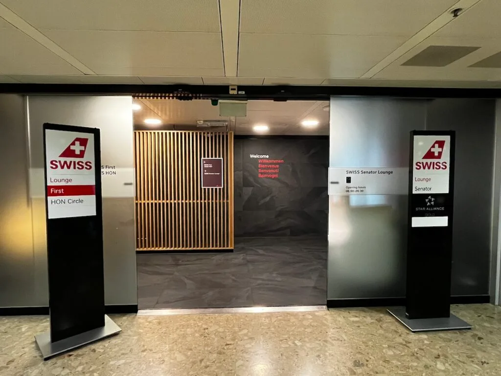 Eingang zur SWISS First Class Lounge mit Schildern und Holzpaneelen