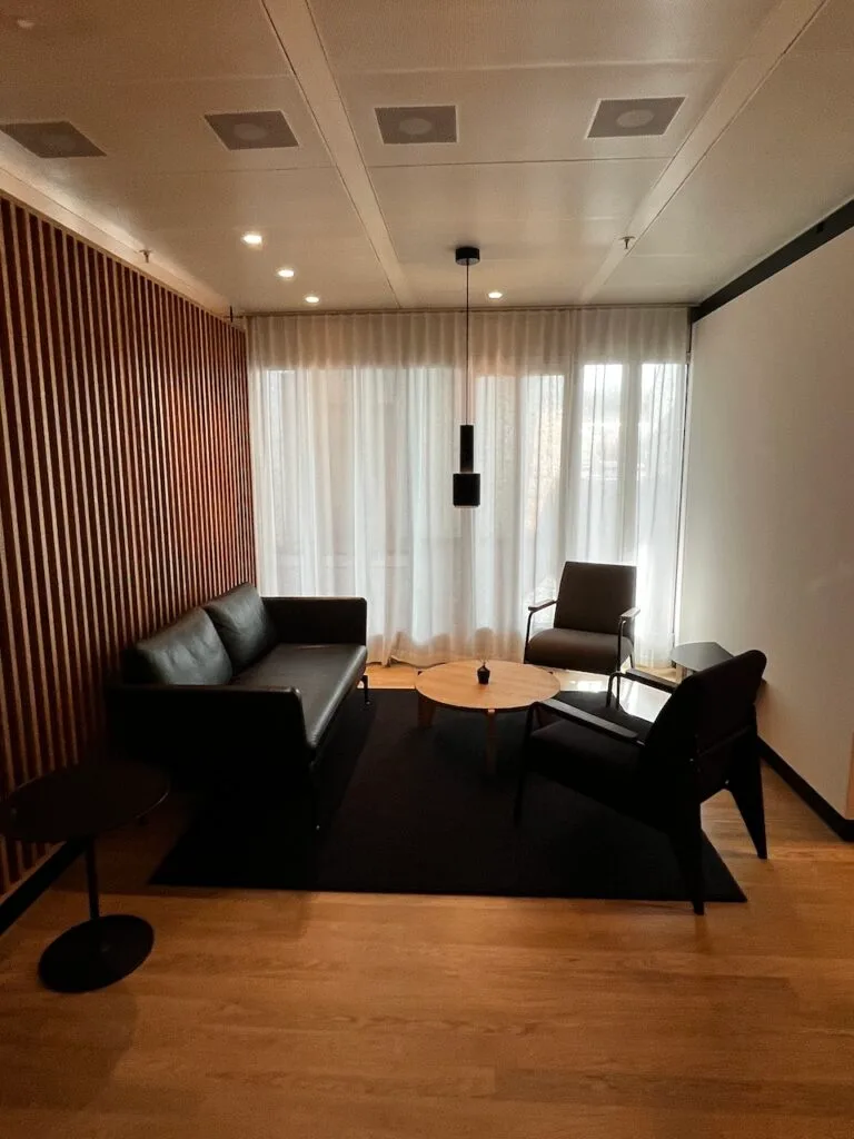 Lounge mit schwarzen Möbeln und Holzwand