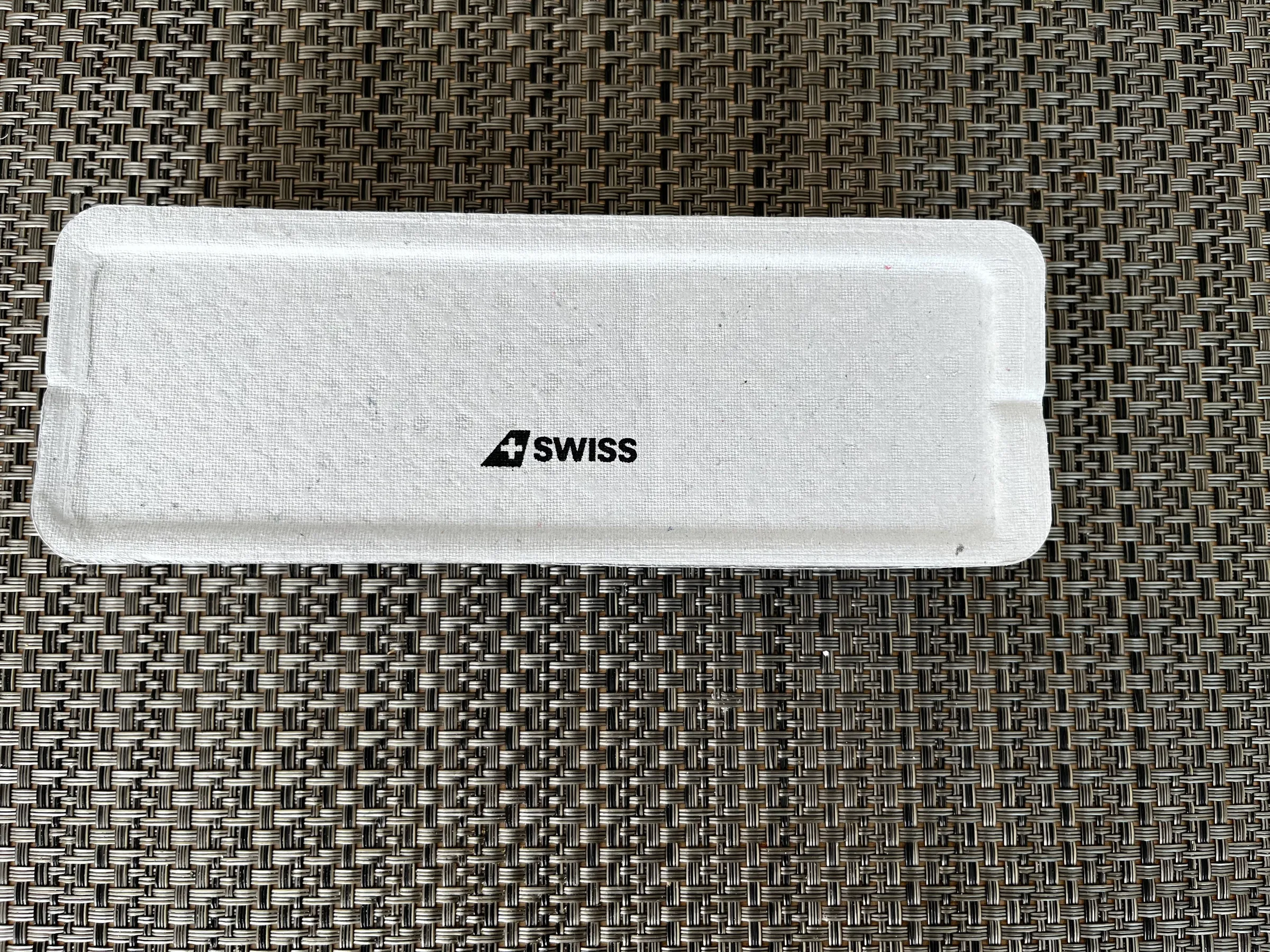 Weißer Etui mit Aufschrift 'SWISS' auf Textiloberfläche
