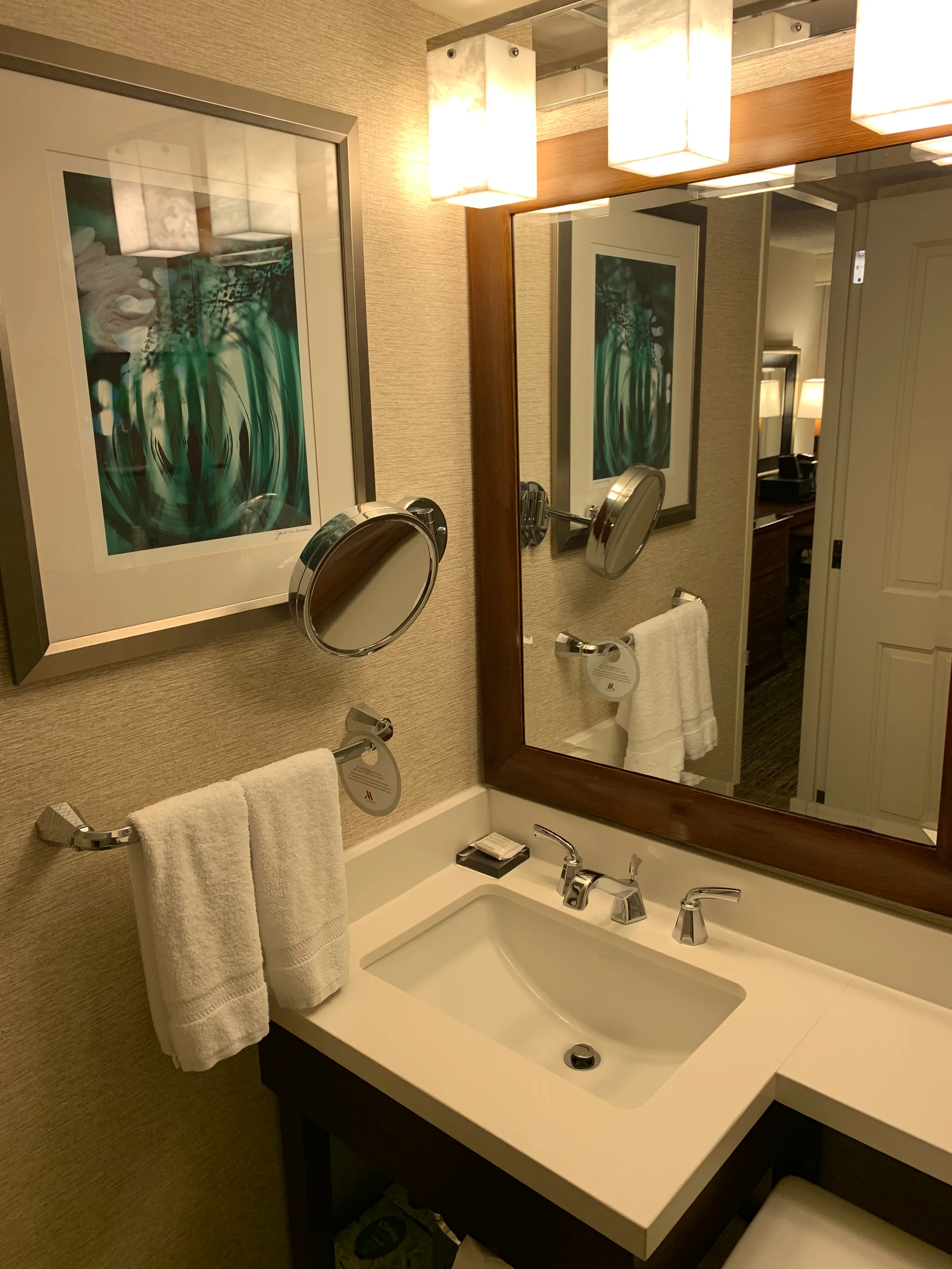 Hotelbadezimmer mit Waschbecken, Spiegel und Handtuchhalter