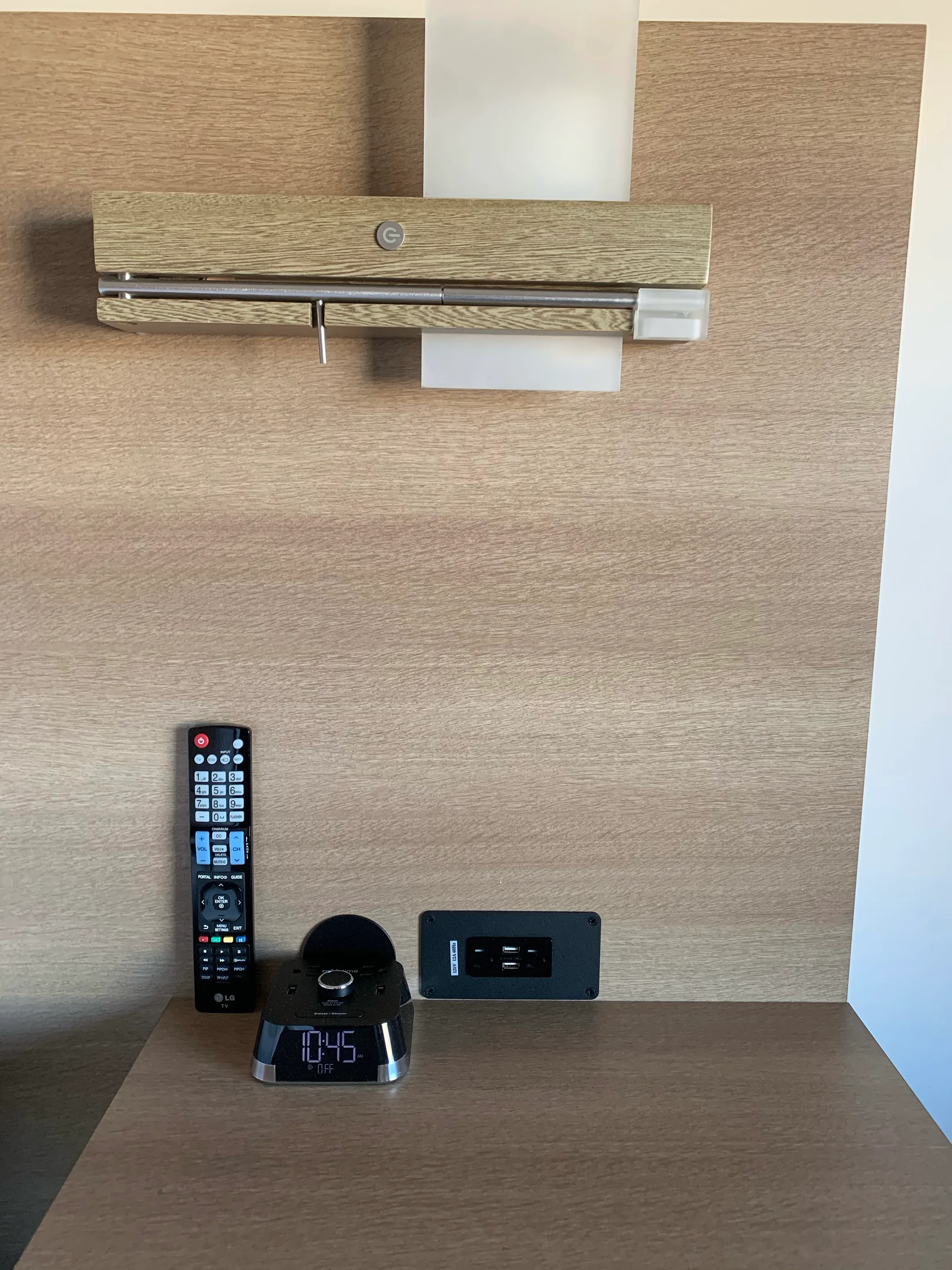 Hotelzimmer mit Fernbedienung, Wecker und Steckdose an der Wand
