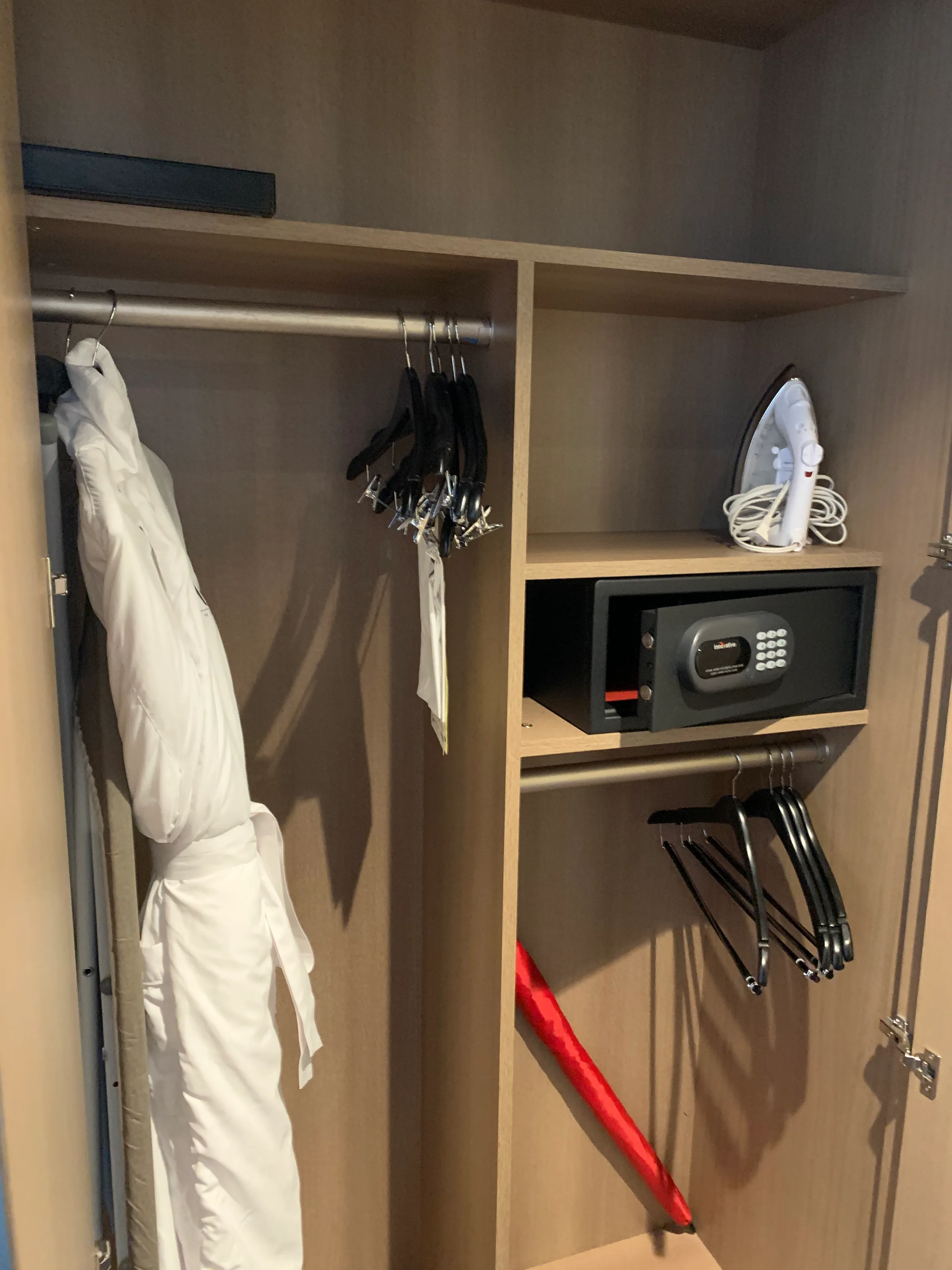 Schrank mit Kleiderbügeln, Wäschekorb und elektrischem Bügeleisen