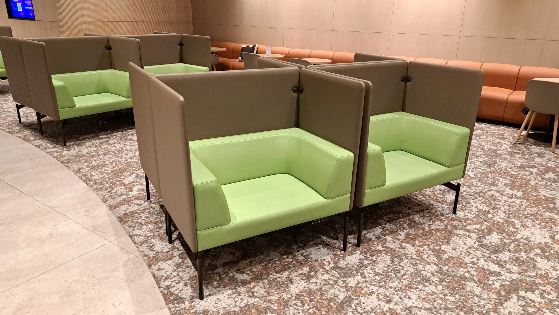 Graue Sitzmöbel mit grünen Polstern in einem Flughafensalon