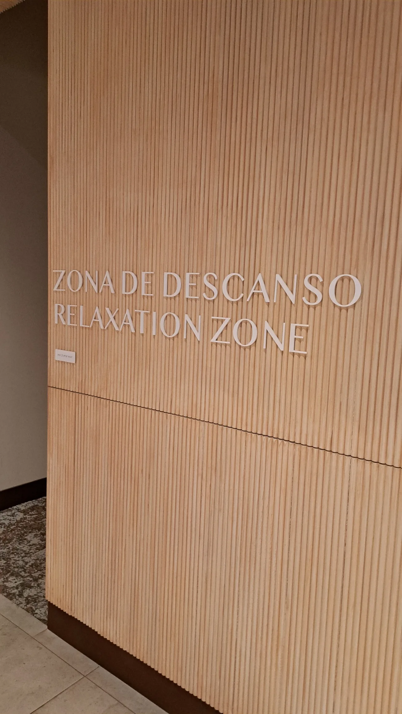 Relaxationsbereich mit Holzwand und Schilderung 'Zona de Descanso' und 'Relaxation Zone'