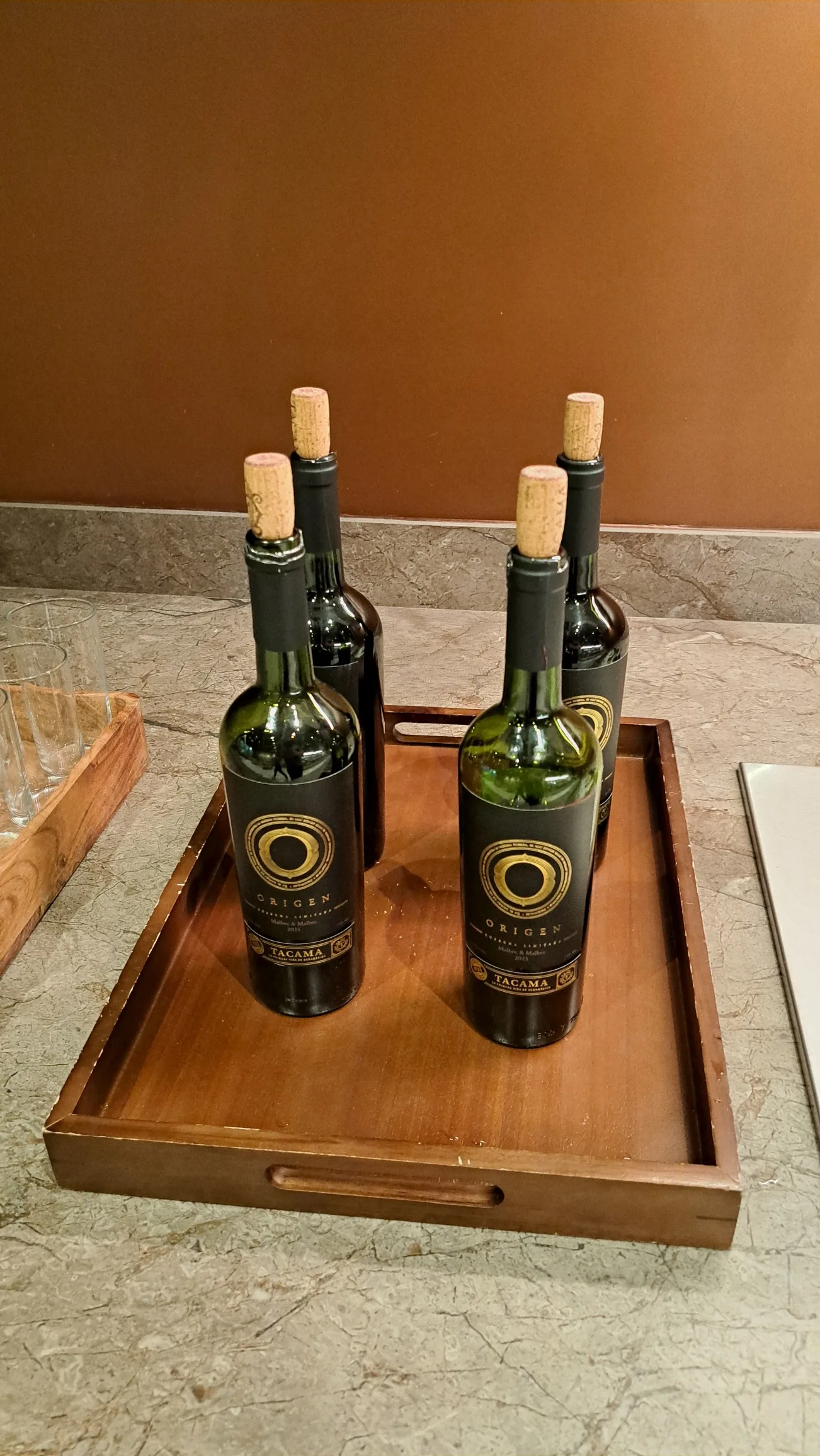 Holztablett mit vier Flaschen Wein auf Marmorplatte