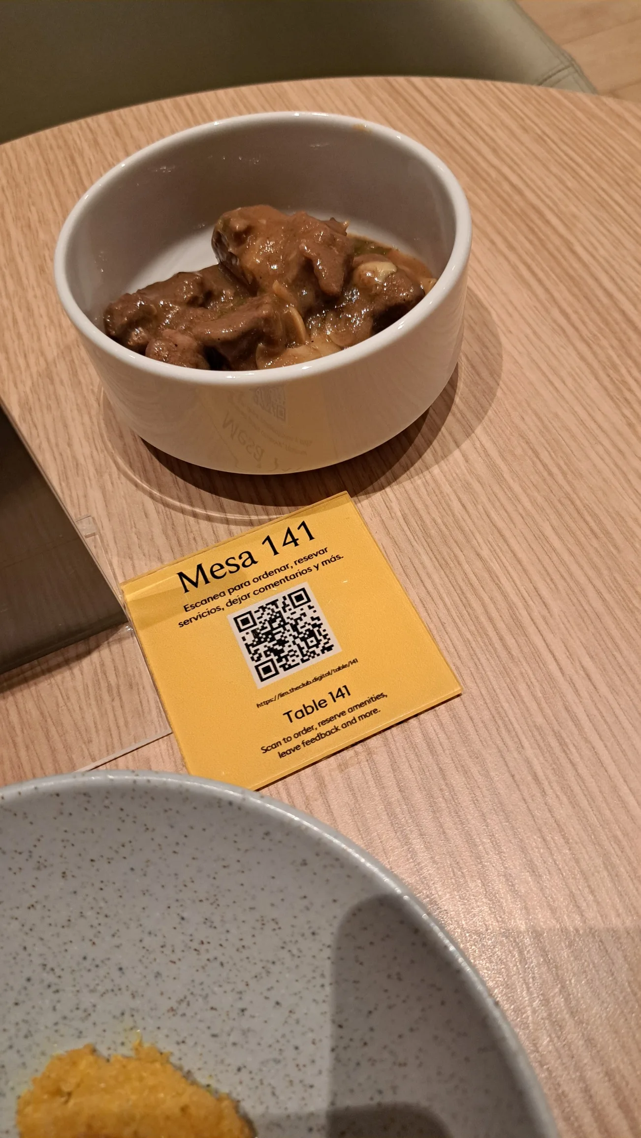 Gericht mit Fleisch in Soße auf Teller mit QR-Code und Tischnummer