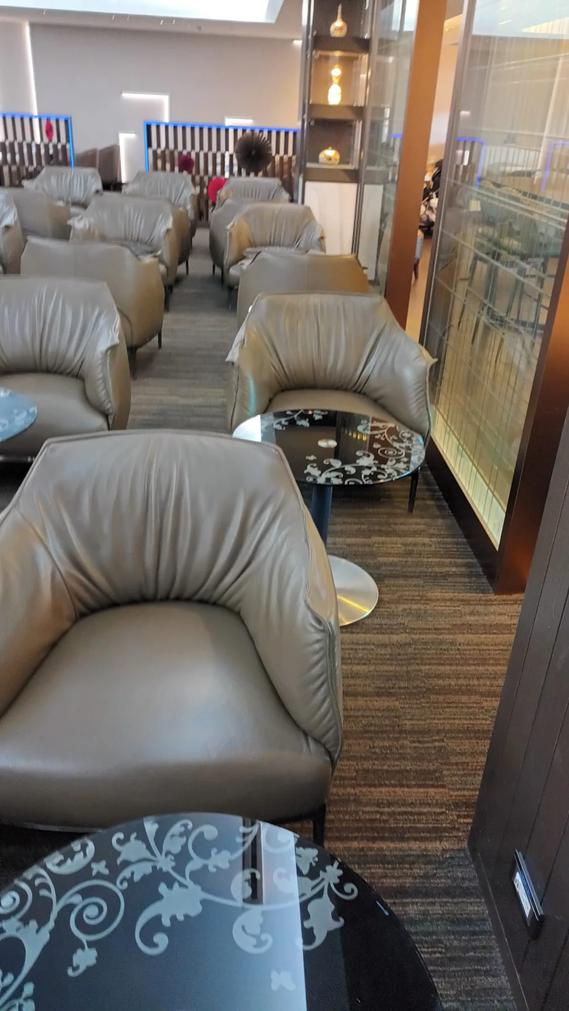Lounge mit grauen Ledersesseln und glänzenden Couchtischen