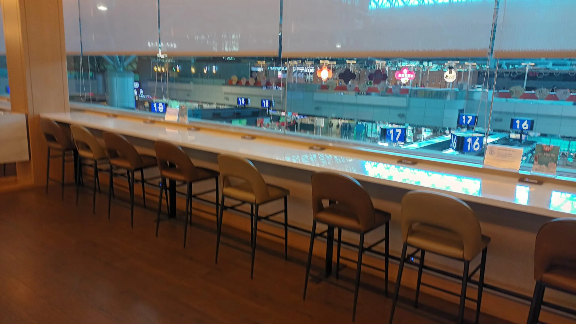 Barhocker vor einem Flughafenlounge-Glasfenster